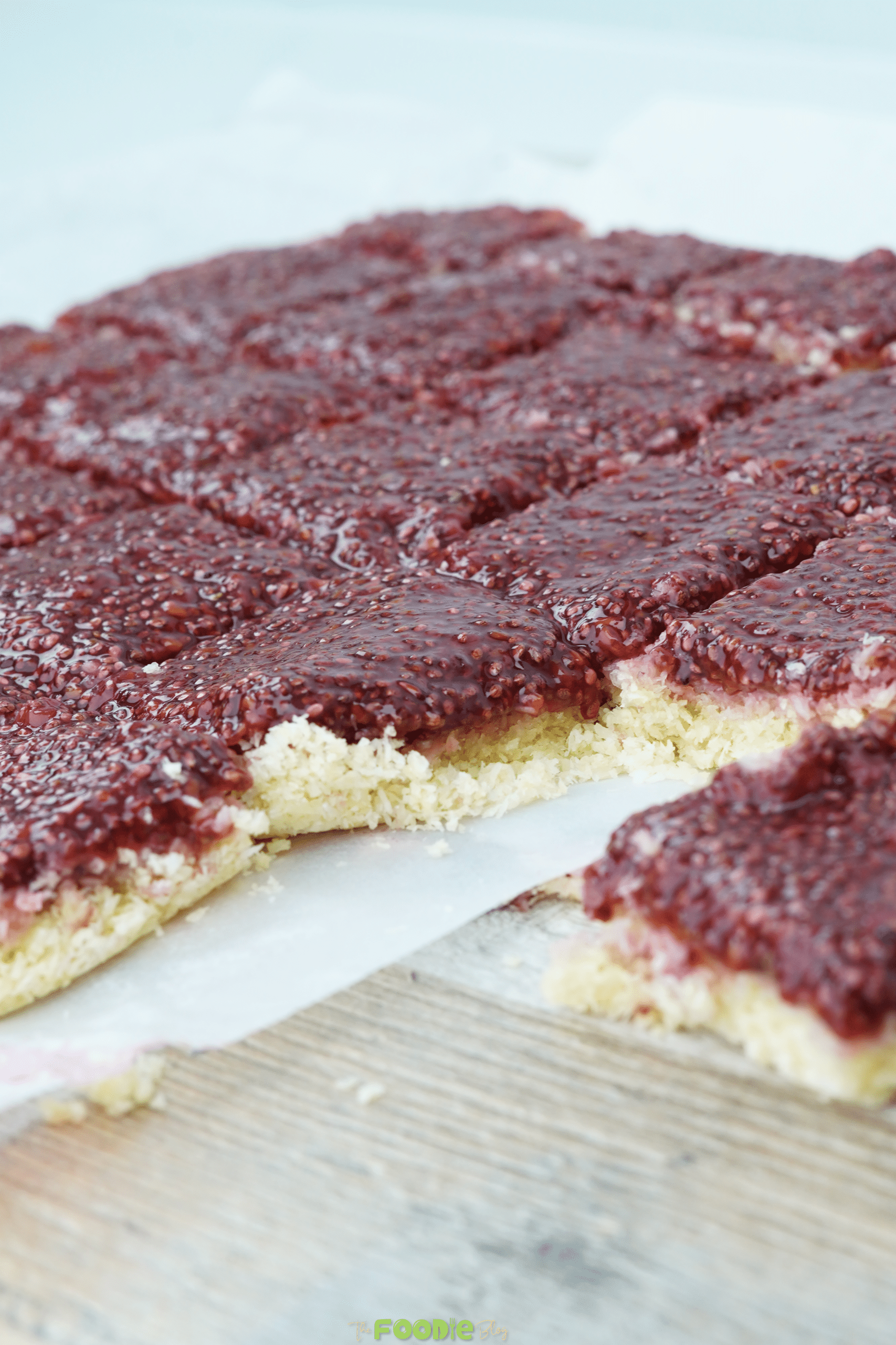 Sliced healthy coconut raspberry bars with a thick raspberry chia topping