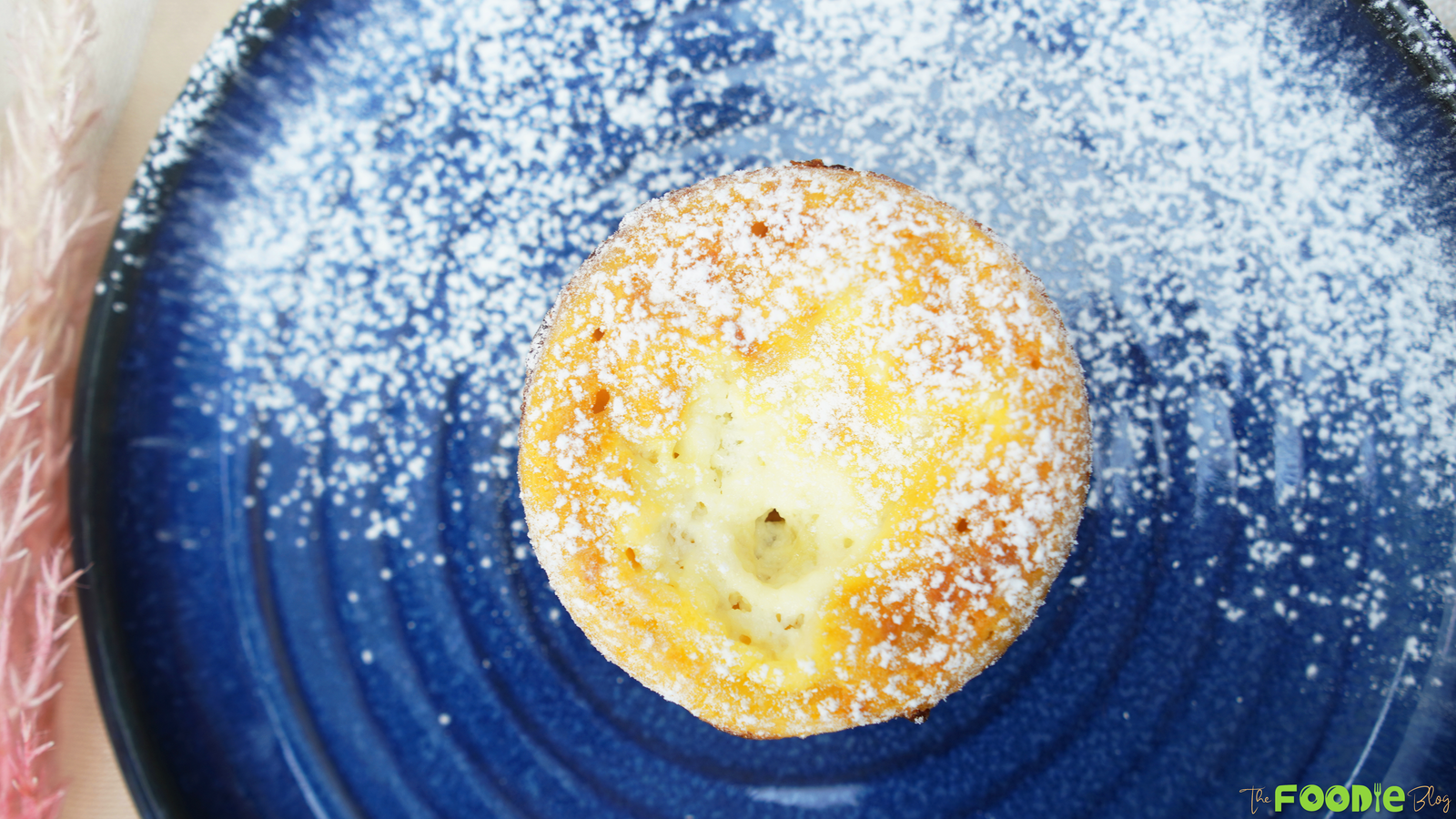 Mini ramekin yogurt cake dusted with powdered sugar on a blue plate
