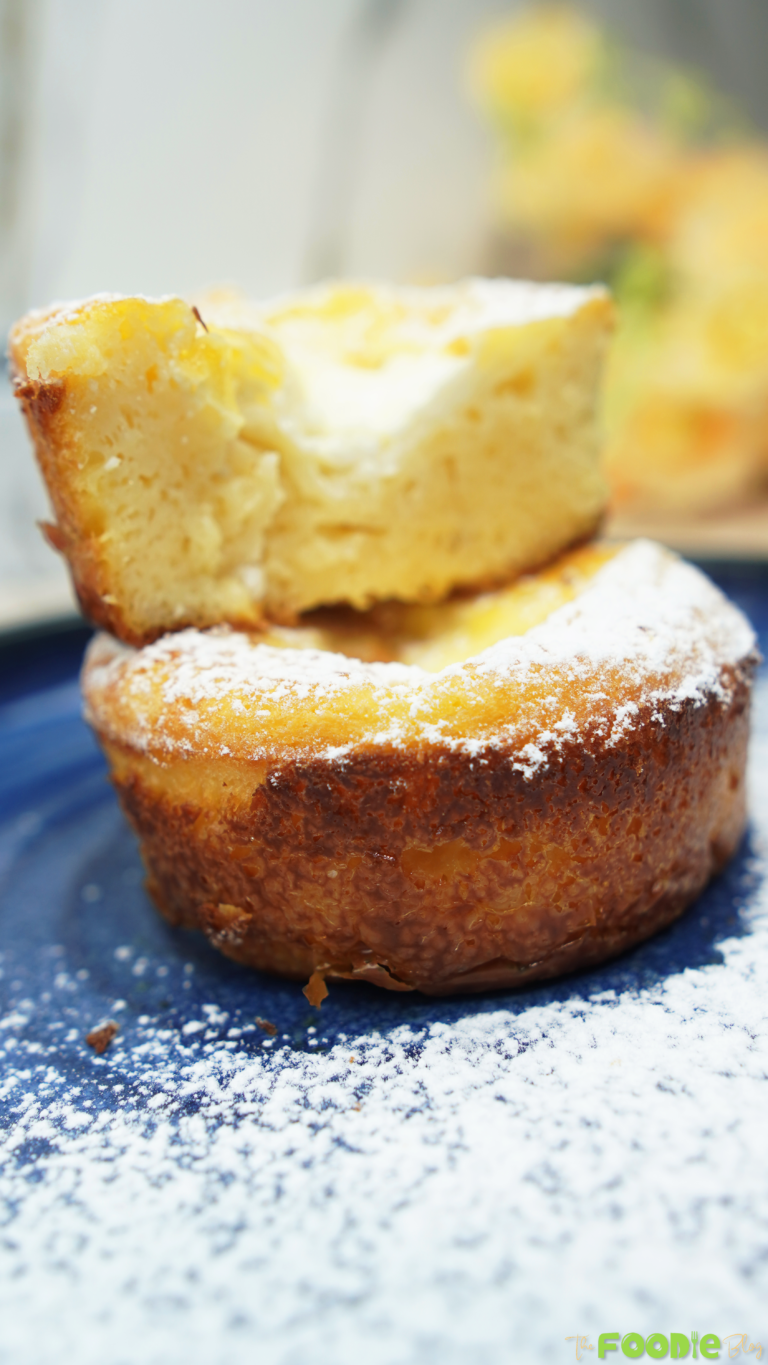 Two mini ramekin cakes stacked with powdered sugar on a blue plate