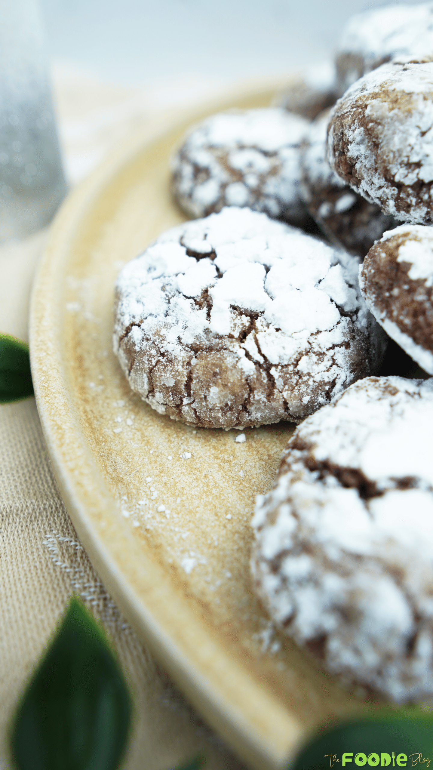 Close-up of powdered sugar–coated cocoa crinkle cookies on a ceramic plate