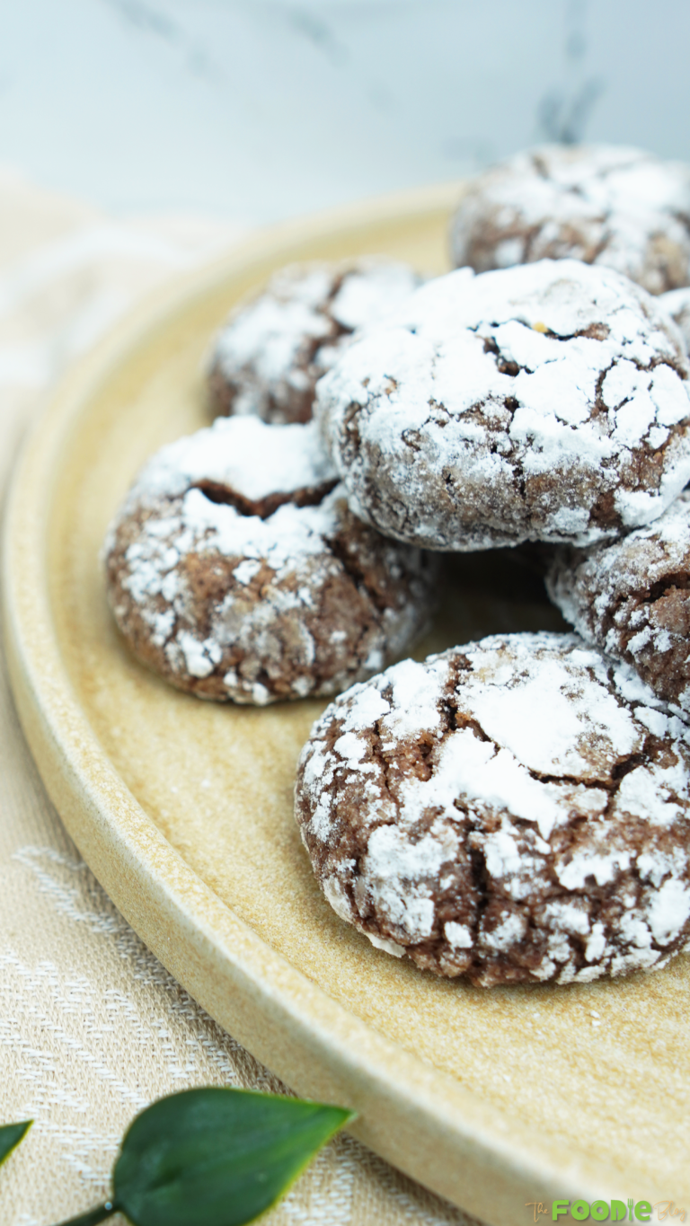 Close-up of powdered sugar–coated cocoa crinkle cookies on a ceramic plate