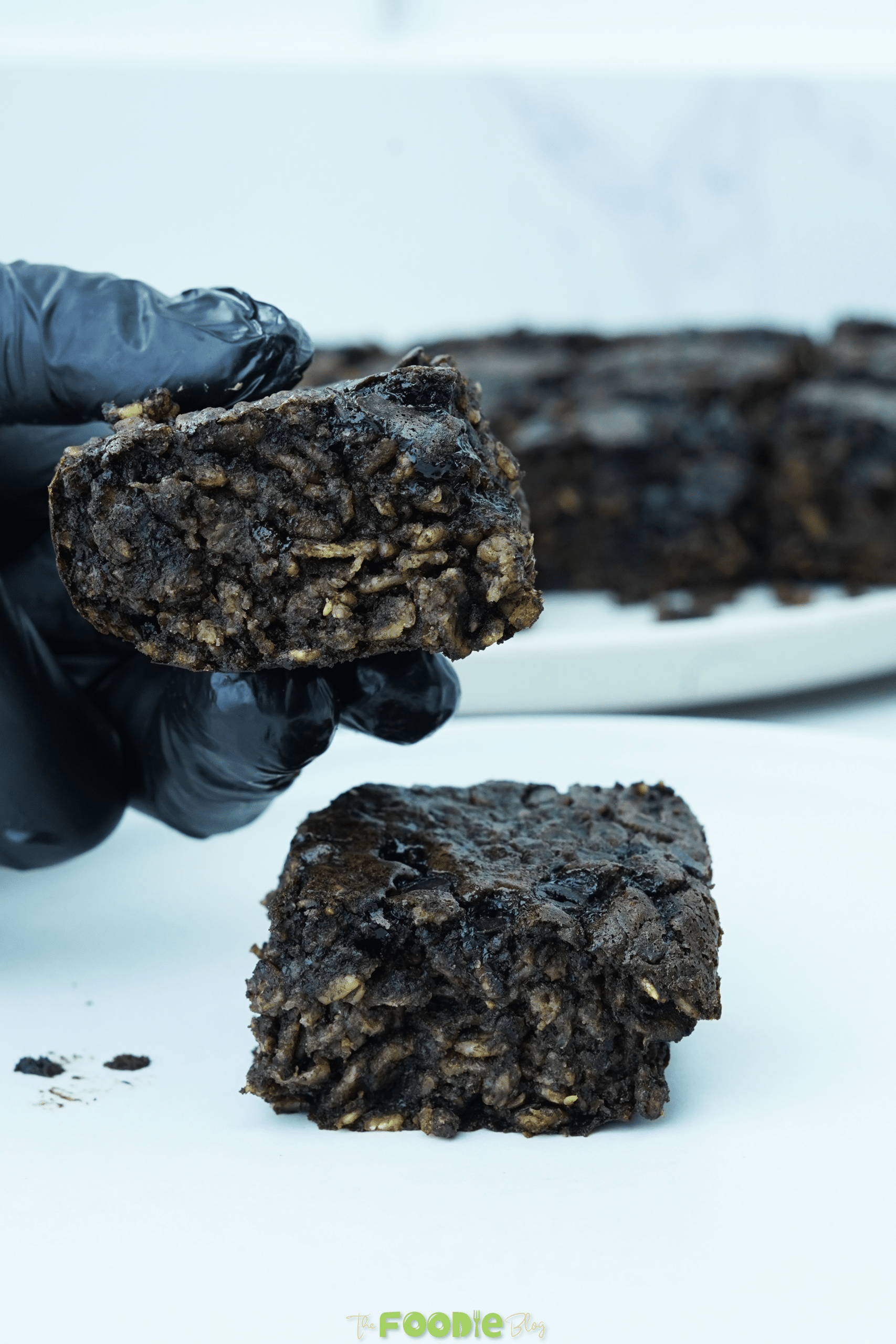 Hand holding a fudgy oatmeal brownie square with oats and chocolatey crumb