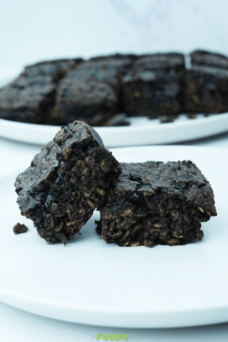 Two oatmeal brownie squares stacked on a white plate