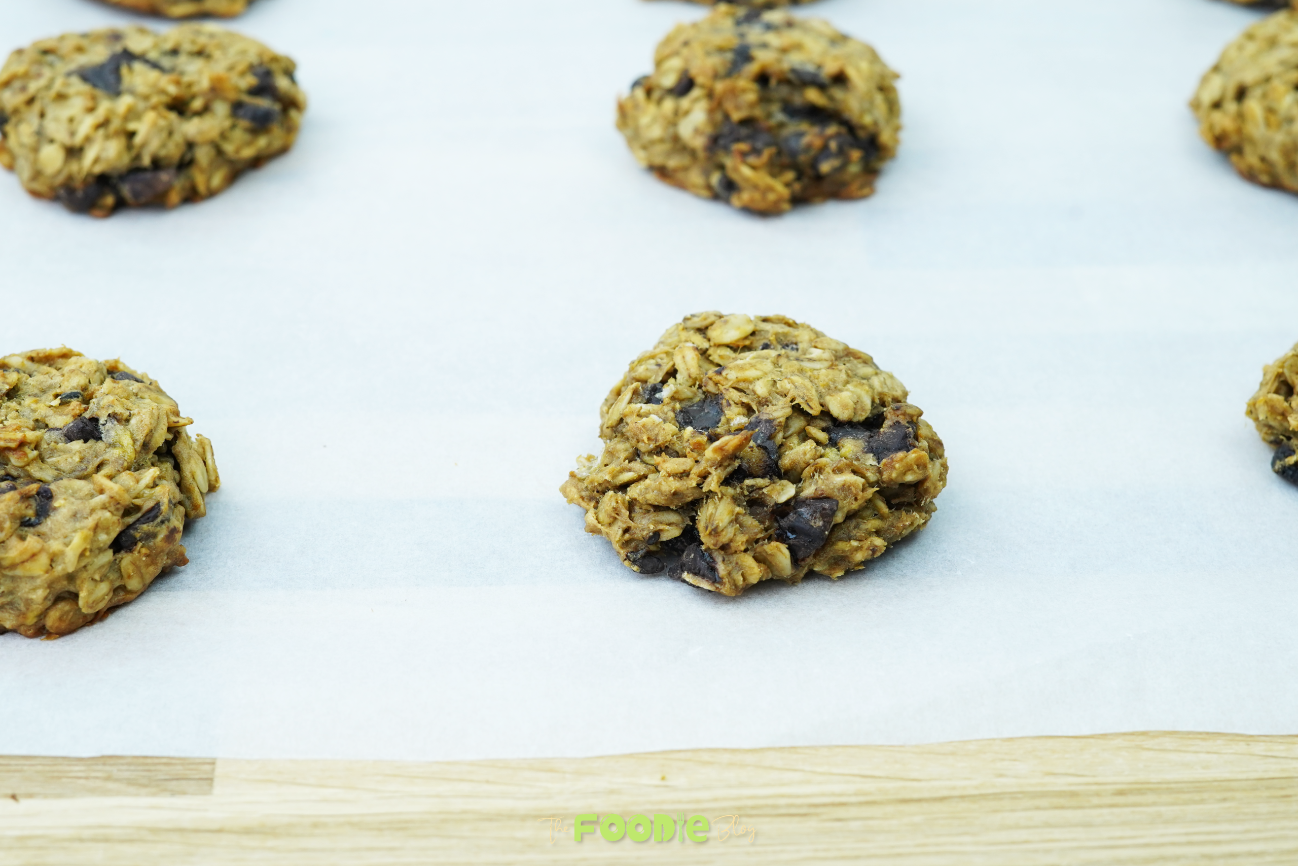 baked oatmeal chocolate chip cookie portions on a parchment-lined cookie sheet