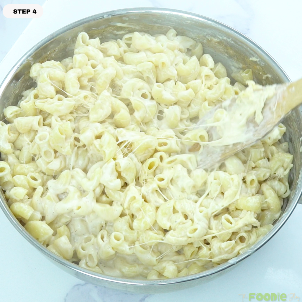 Cheesy macaroni being stirred in a pan with stretchy melted cheese