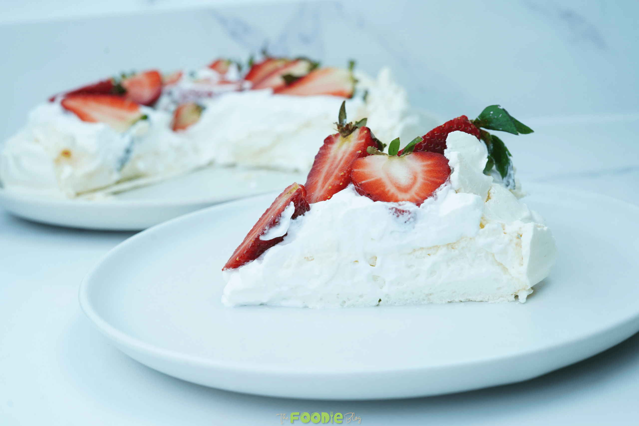 Close-up of a pavlova slice with whipped cream and strawberries on a plate