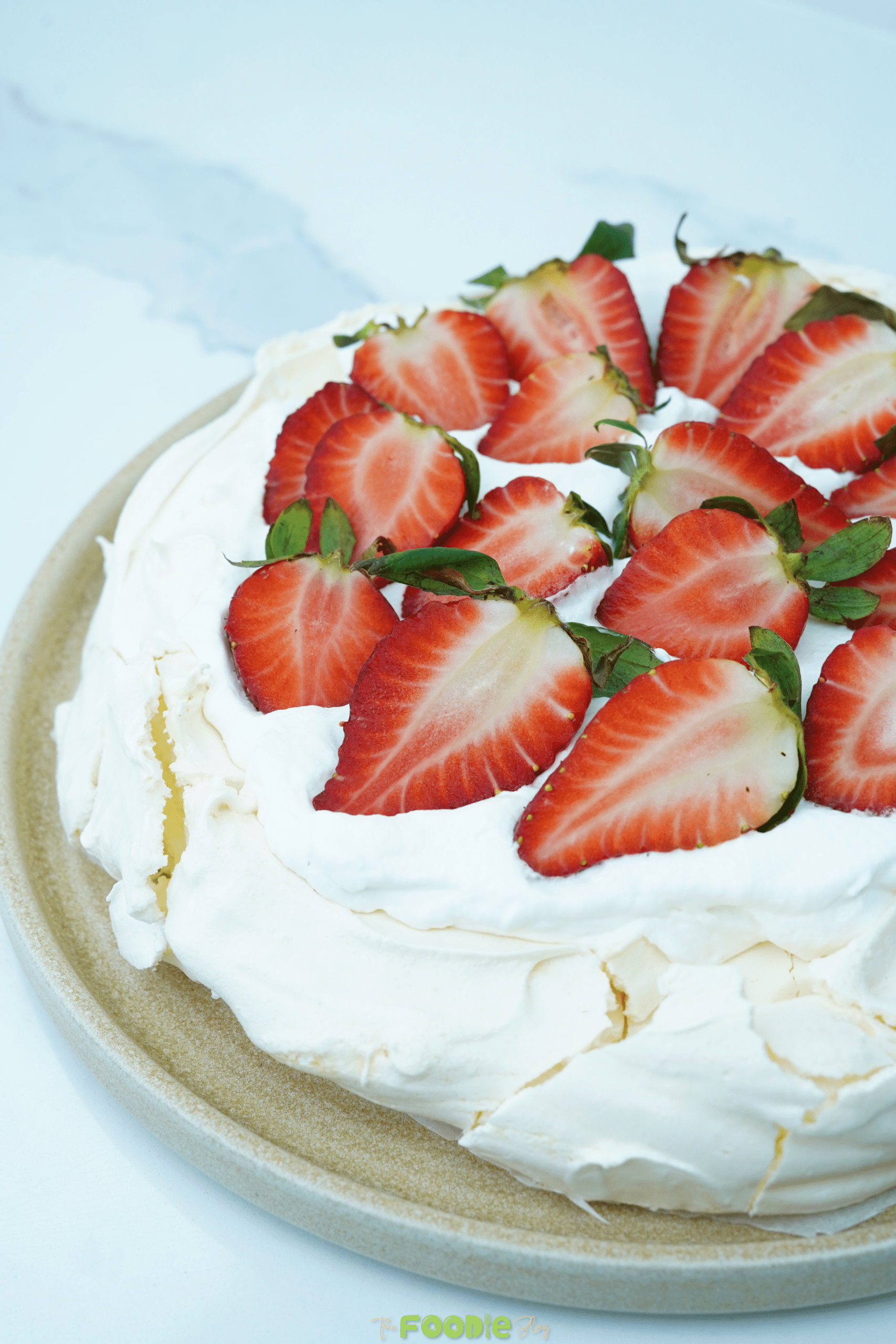 Close-up of strawberry-topped pavlova showing the crackly meringue surface and whipped cream