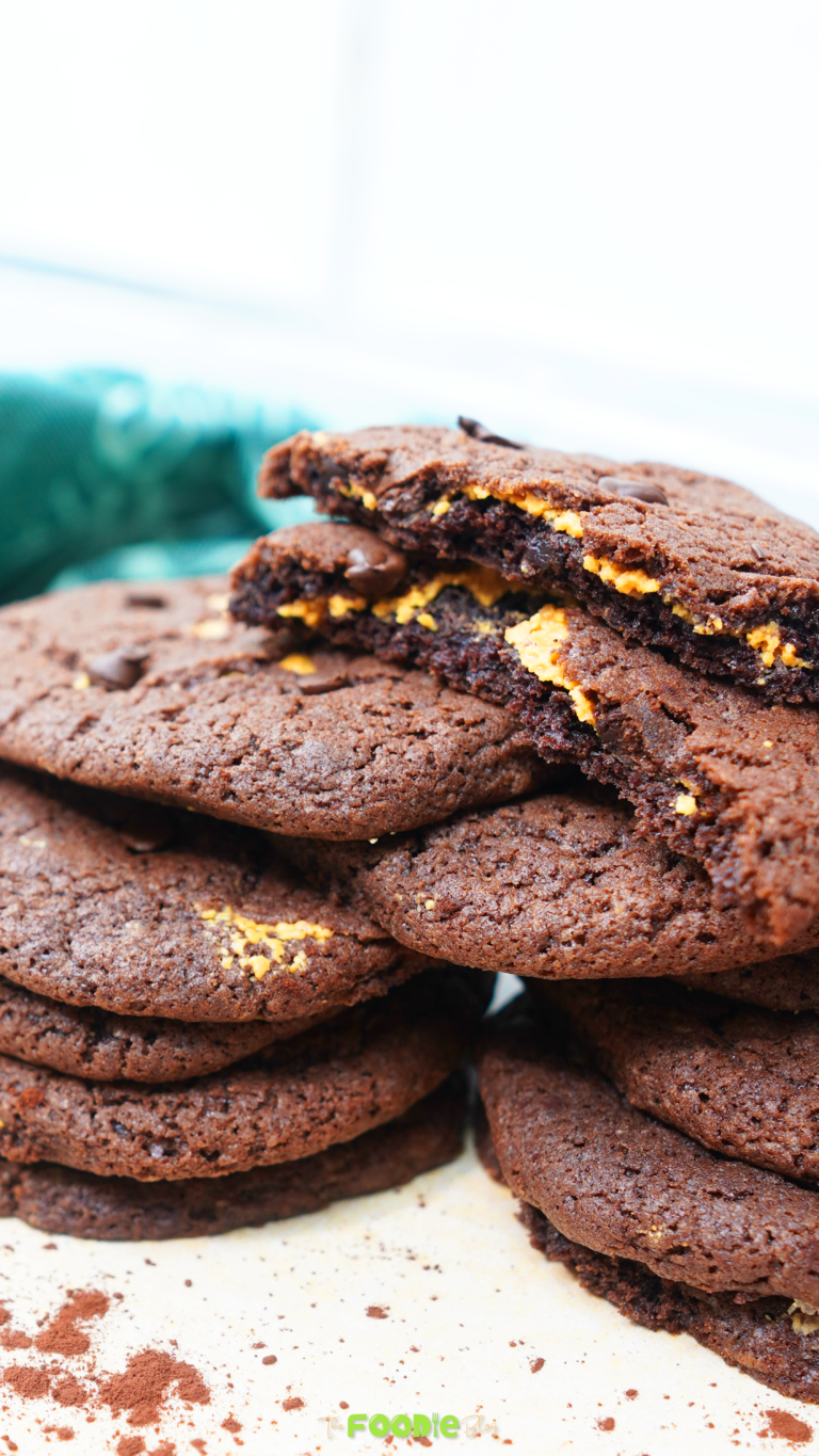 Chocolate peanut butter cookies stacked with a broken cookie showing the peanut butter layer inside