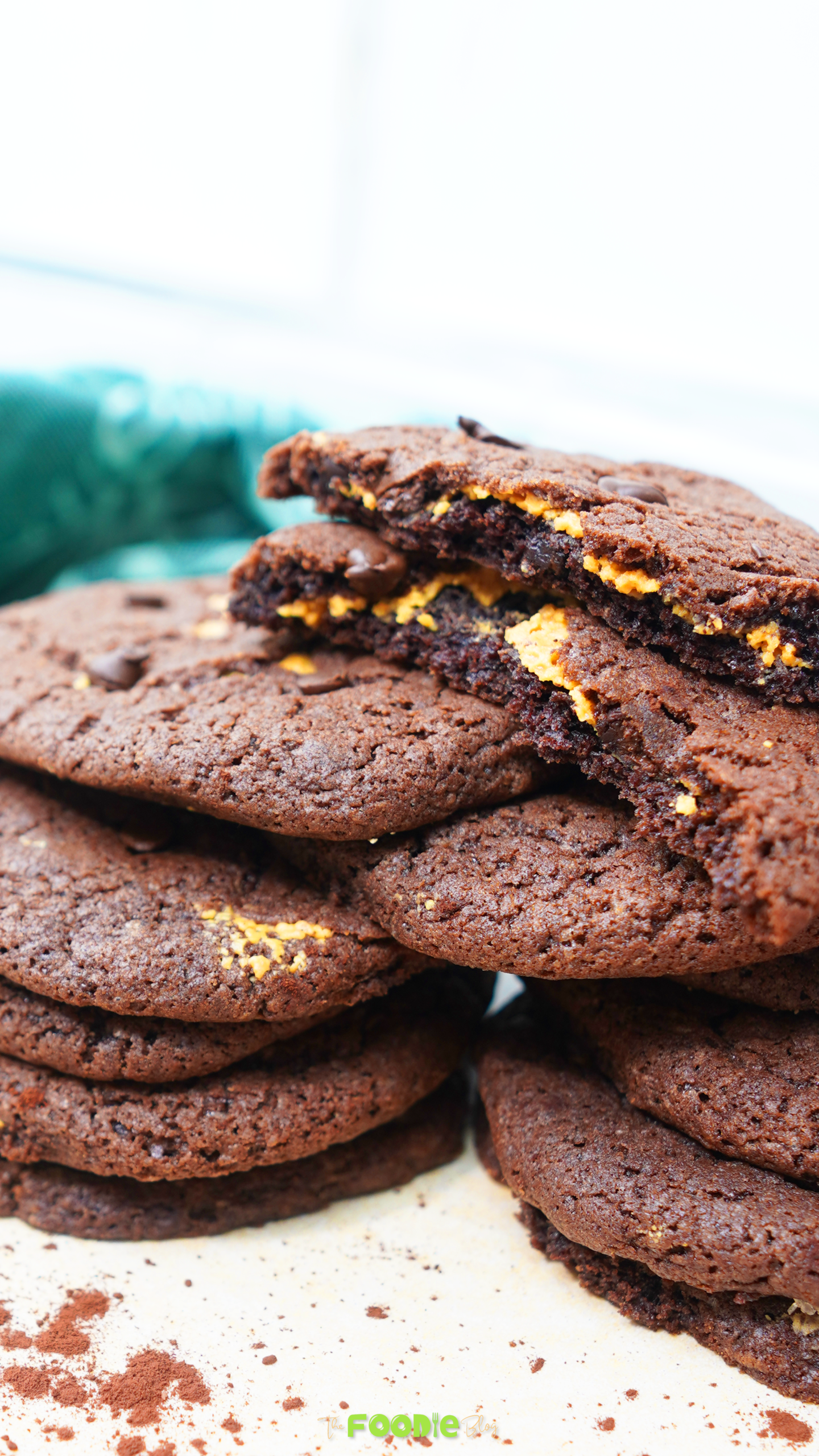 Chocolate peanut butter cookies stacked with a broken cookie showing the peanut butter layer inside