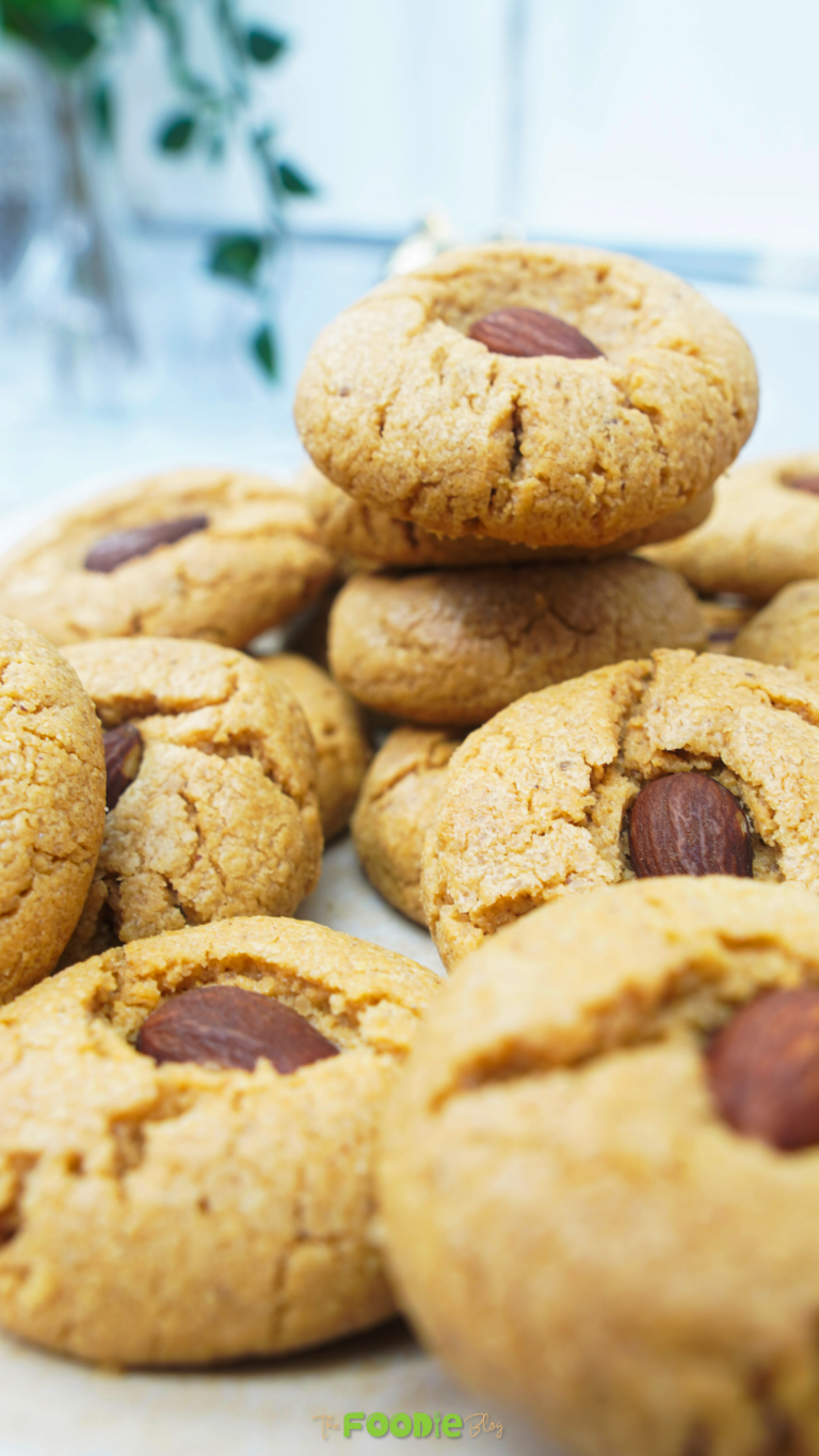 Close-up of peanut butter cookies with crackled tops and an almond pressed in the center
