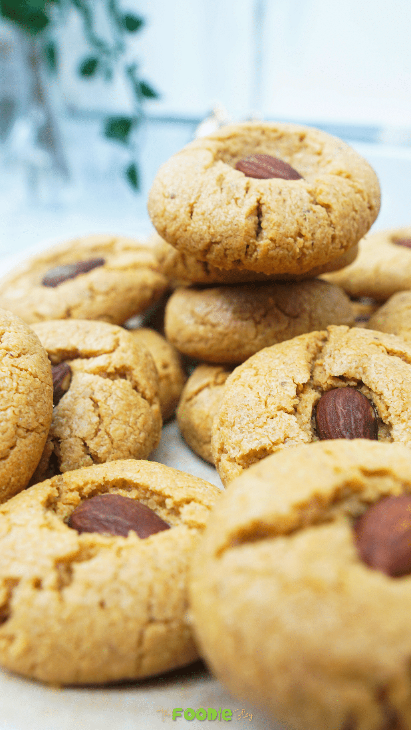 Close-up of peanut butter cookies with crackled tops and an almond pressed in the center