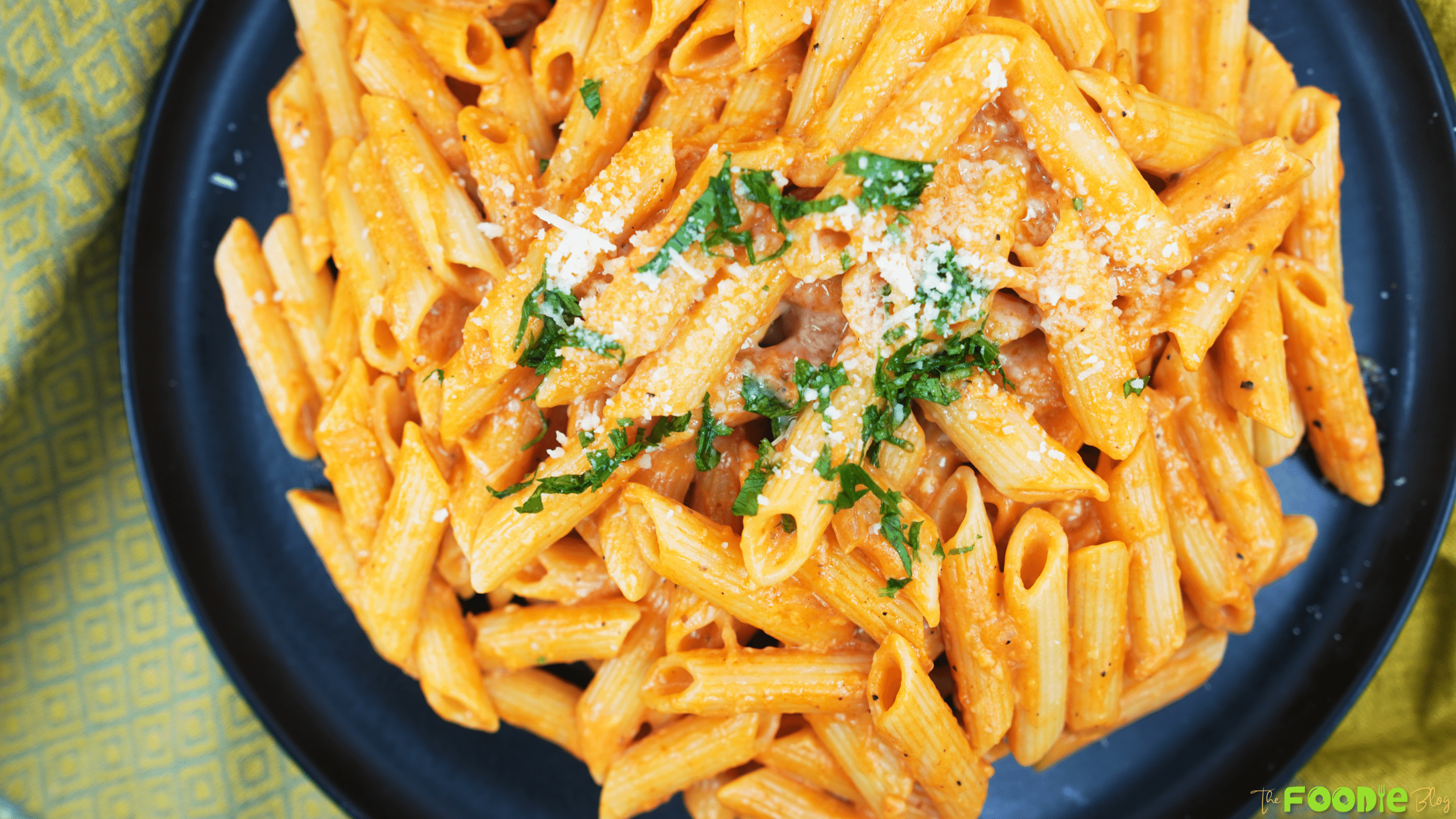 Top-down view of penne coated in creamy vodka sauce topped with grated Parmesan and parsley