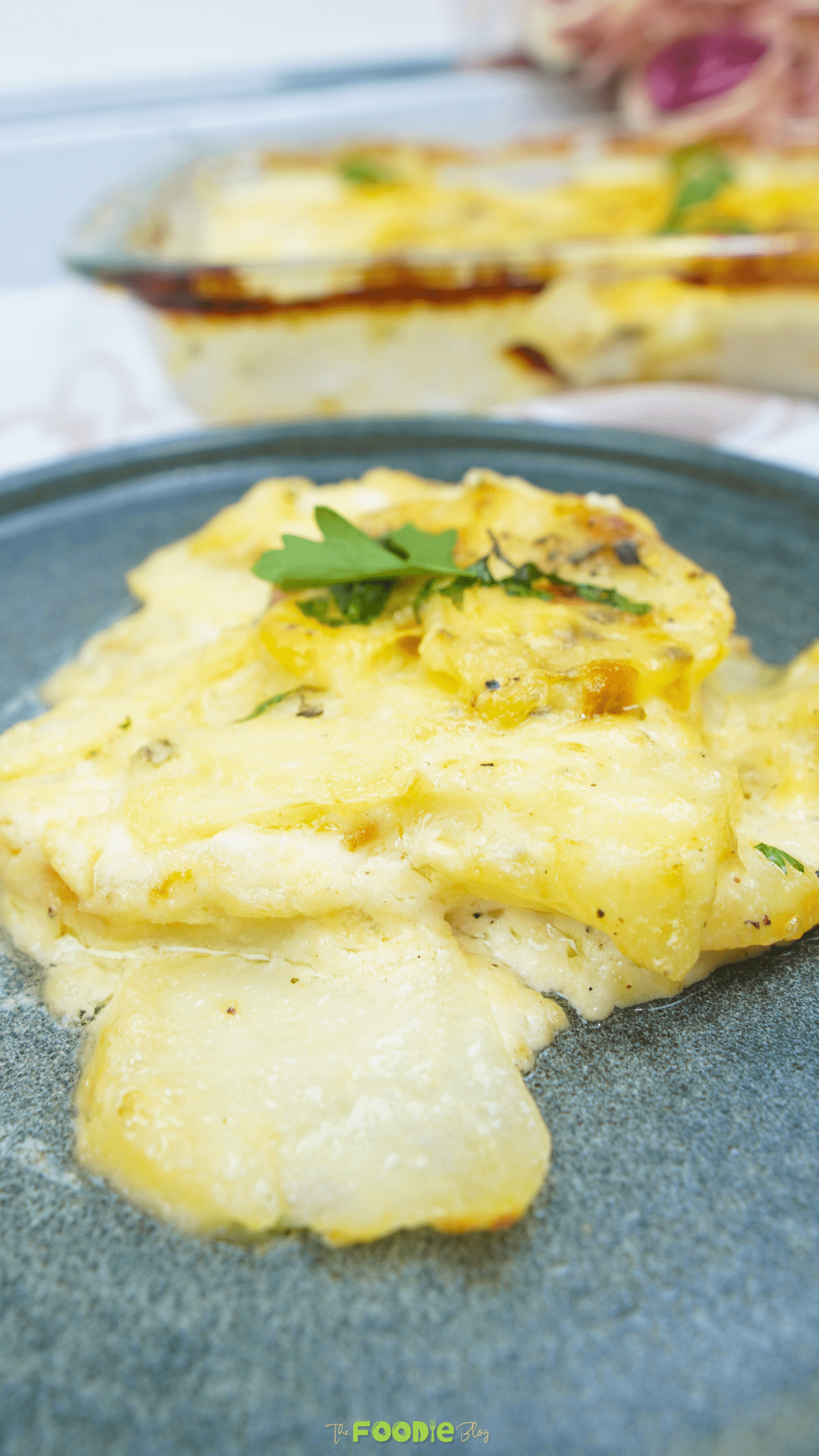 A serving of potatoes au gratin on a dark plate with creamy sauce and a browned top