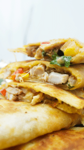 Sliced chicken quesadilla wedges stacked to show the filling and melted cheese