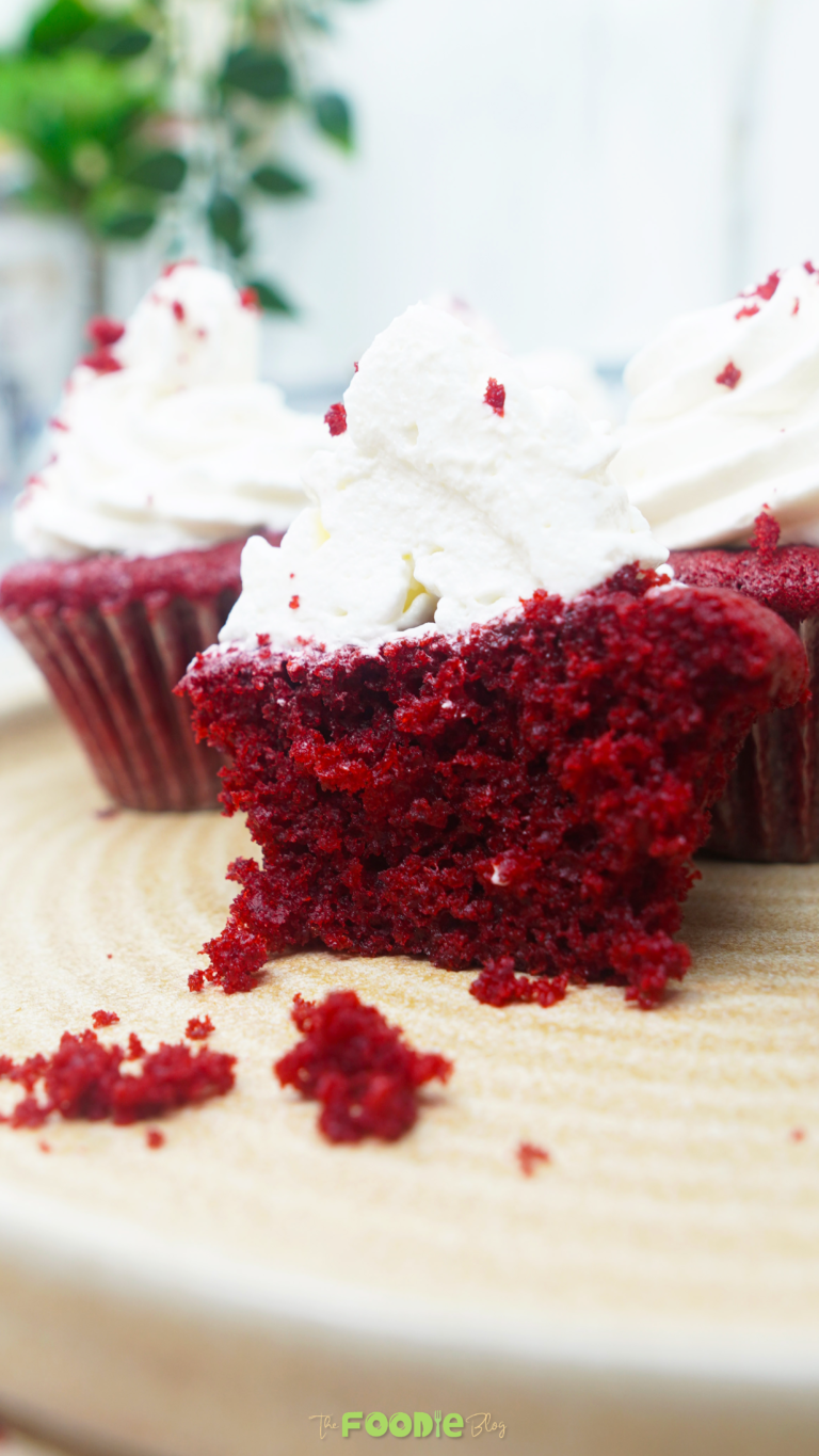 Bite-sized piece of red velvet cupcake with cream cheese frosting in the foreground