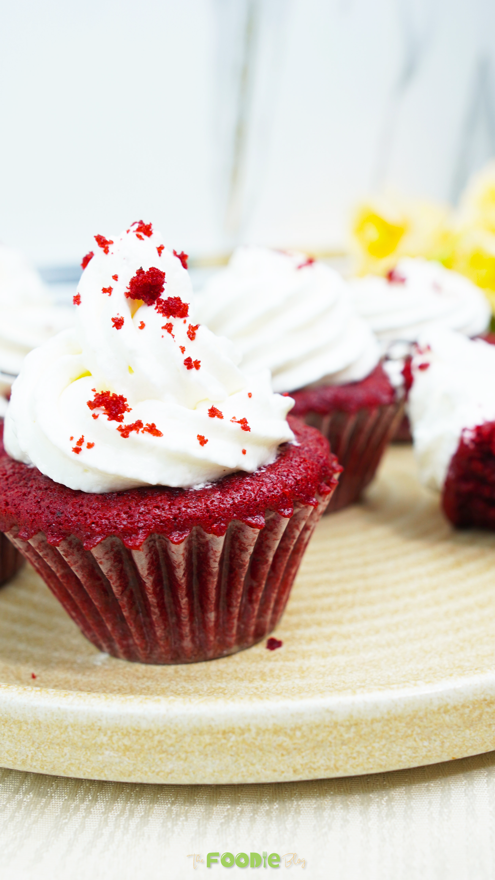 Red velvet cupcake topped with a swirl of cream cheese frosting on a plate
