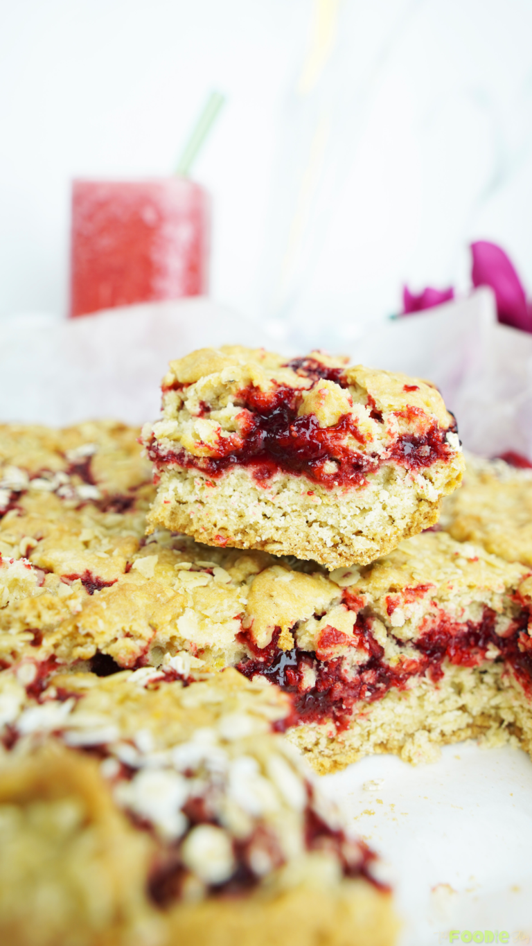 A single raspberry jam oat bar showing the thick jam layer and crumbly oat top
