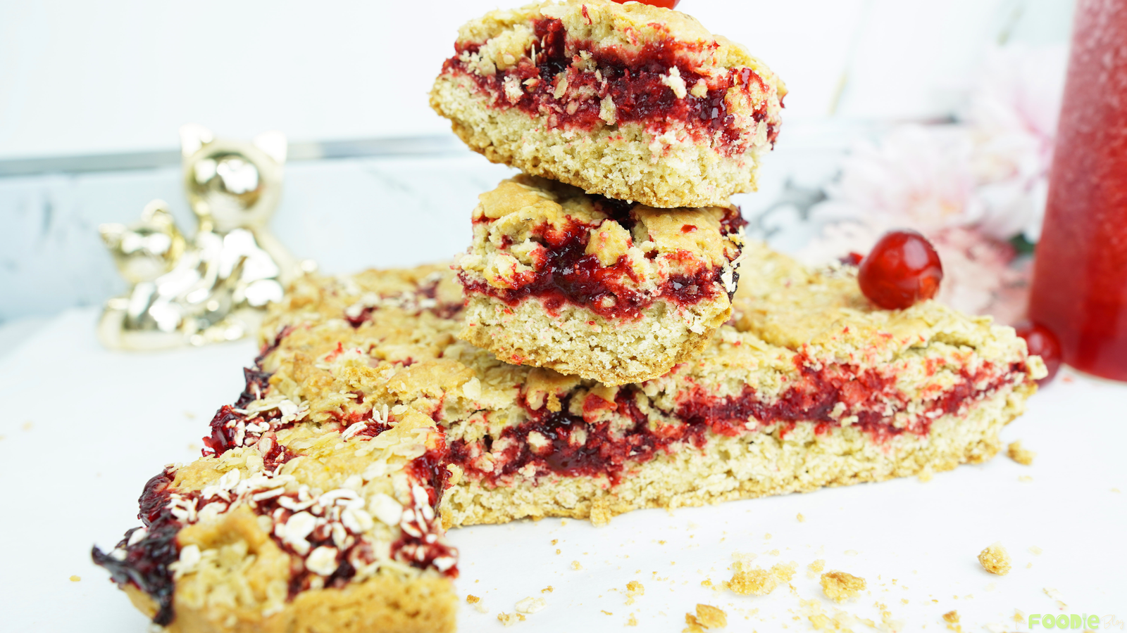Jam-filled oat bars with a raspberry layer and golden crumble topping on a white surface
