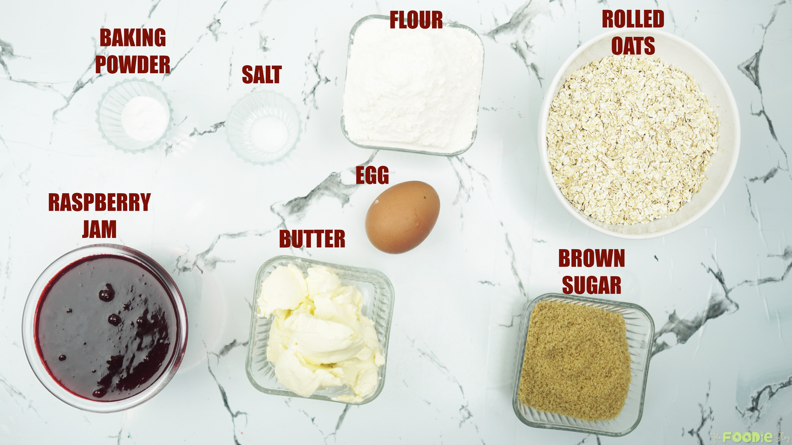 Flour, rolled oats, butter, brown sugar, egg, baking powder, salt, and raspberry jam on a counter
