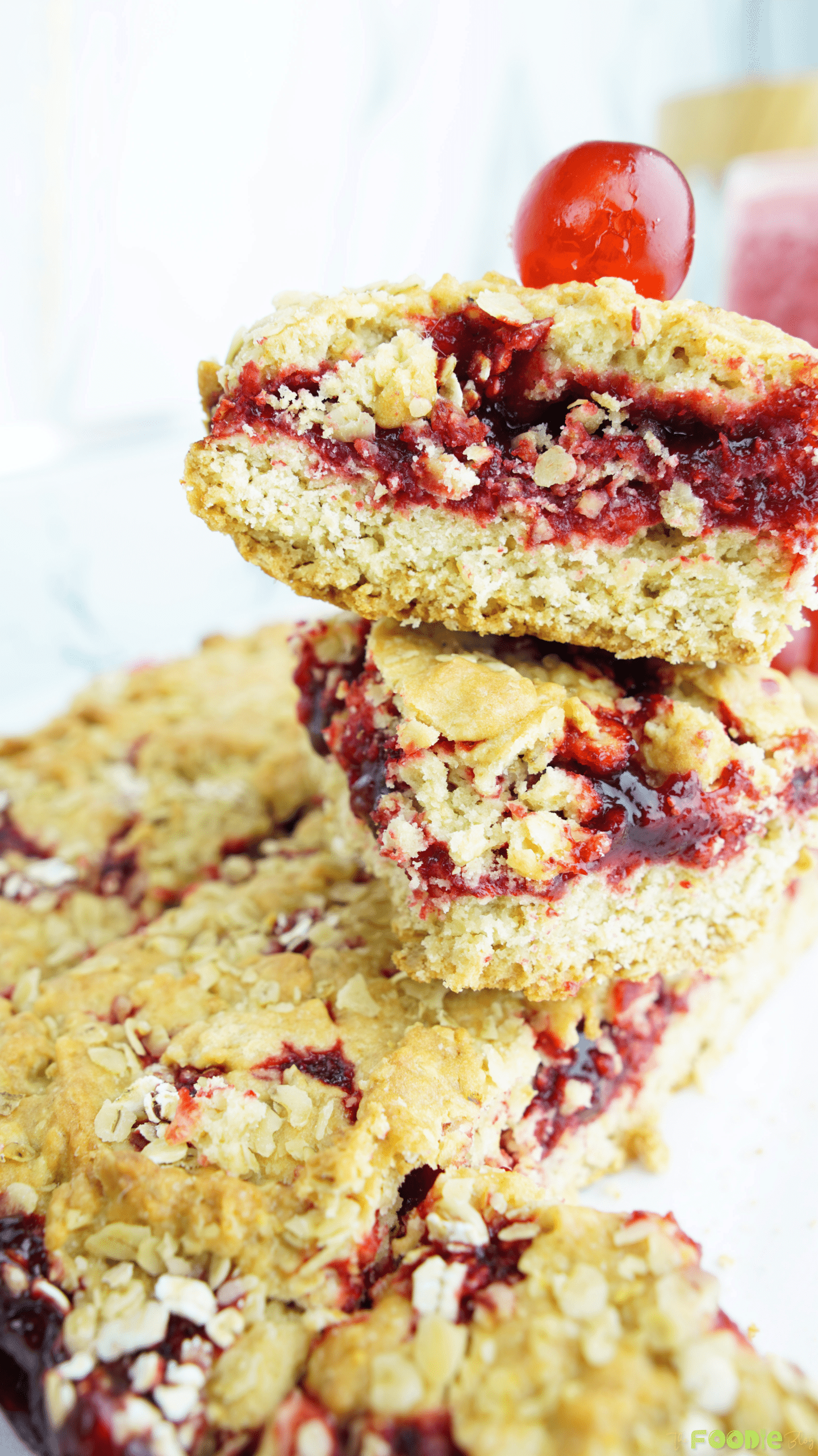Two stacked oat crumble bars with raspberry jam filling and a golden crust