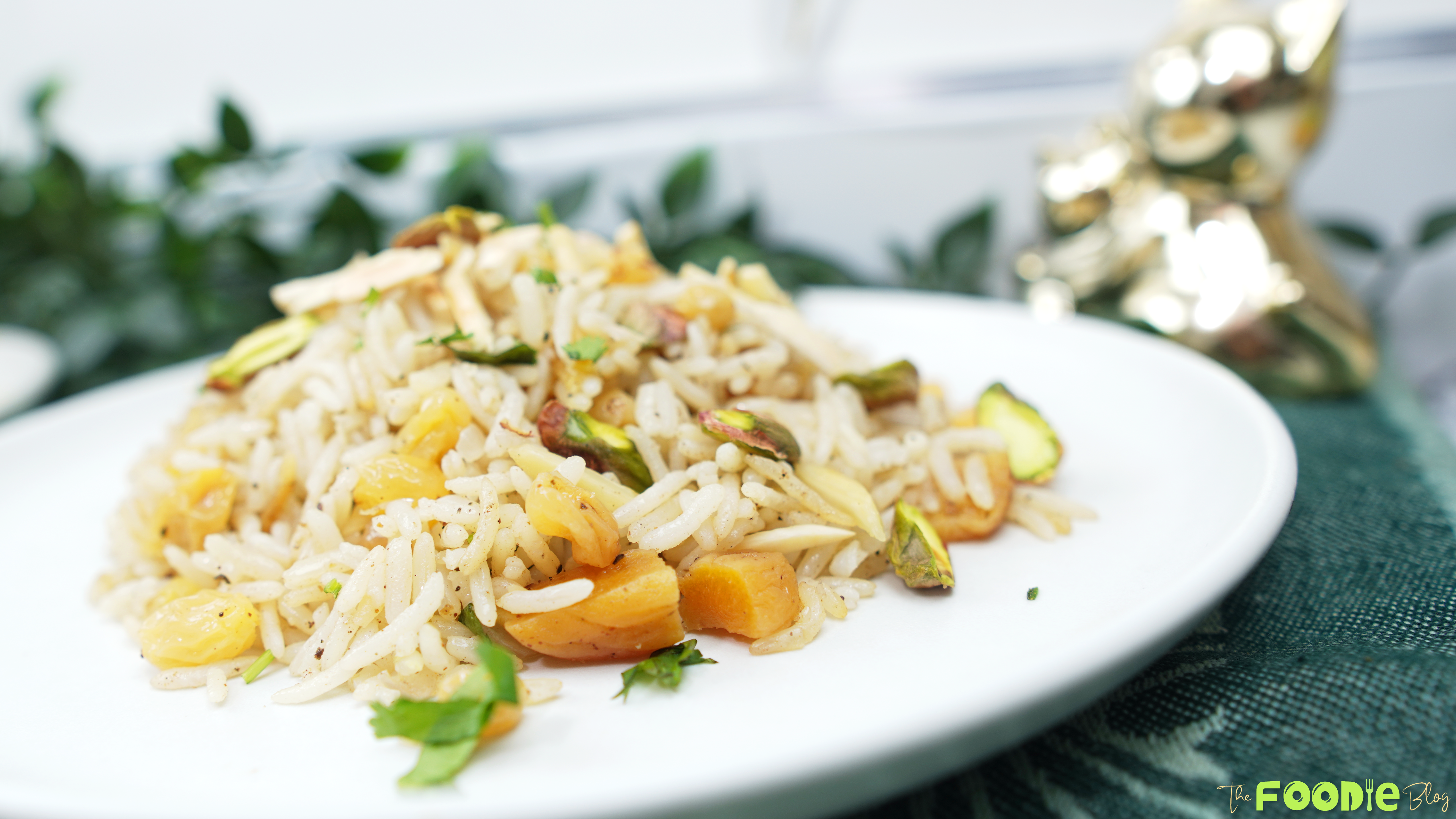 Plated basmati rice pilaf with dried fruit and toasted nuts on a white dish with a soft background