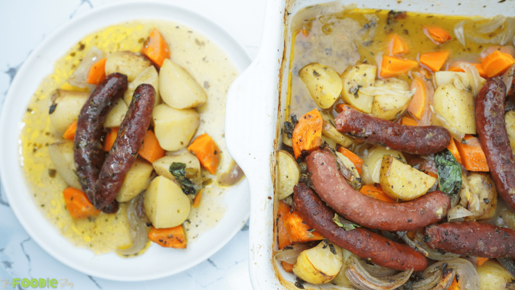 Sausage bake in a baking dish next to a plated serving with potatoes, carrots, and onions
