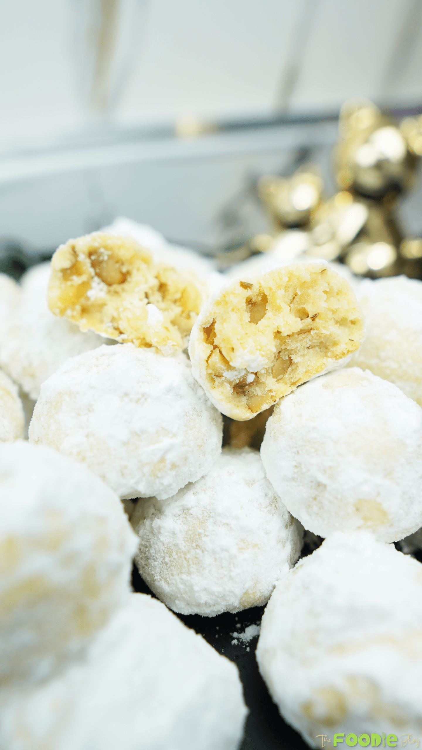 Close-up of powdered sugar snowball cookies with a broken cookie showing walnut pieces