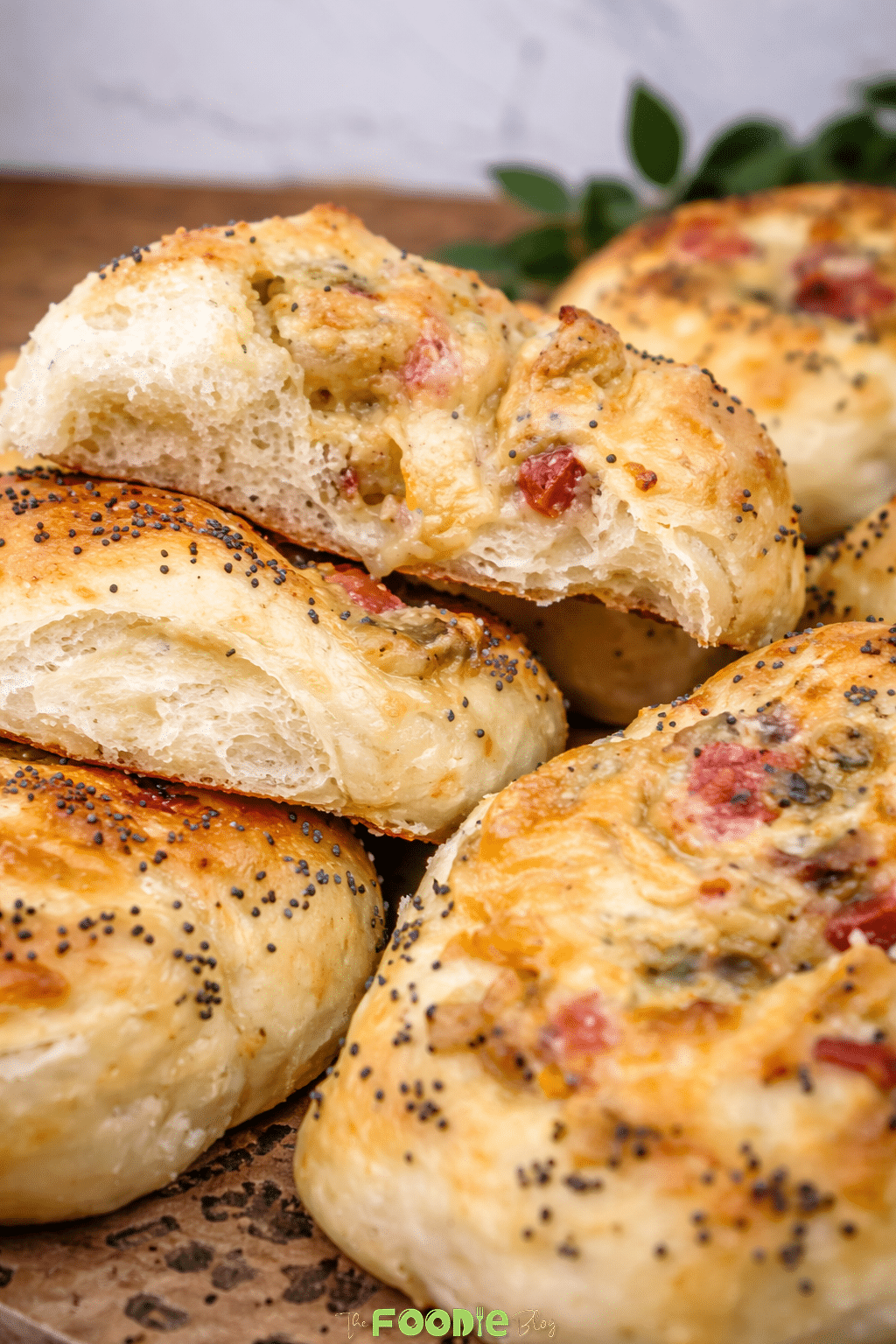 Freshly baked soft cheese pizza buns topped with poppy seeds and cheesy chicken filling, photographed close up.