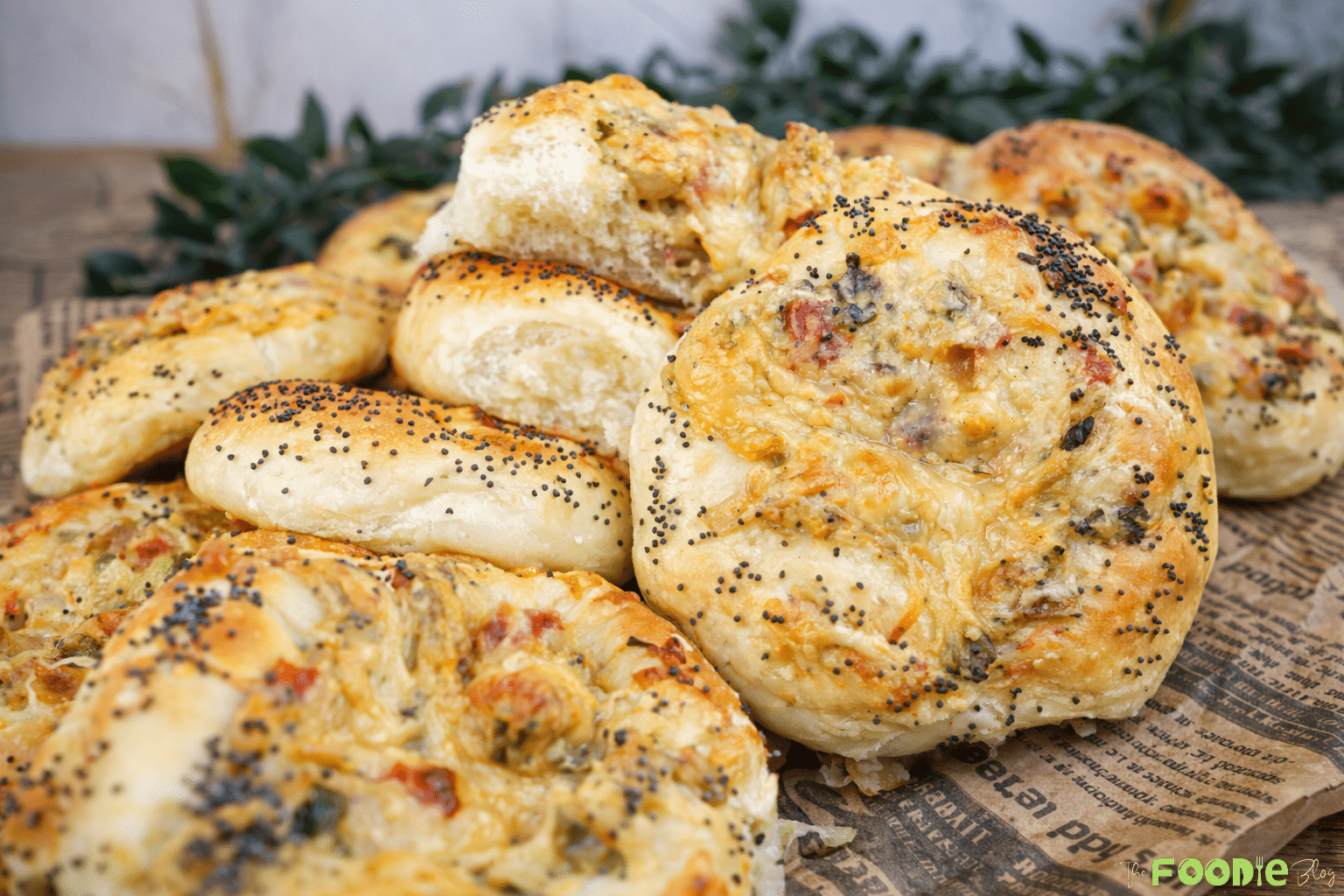 Platter of soft cheese pizza buns topped with poppy seeds and filled with cheese, chicken, onions, and bell peppers.