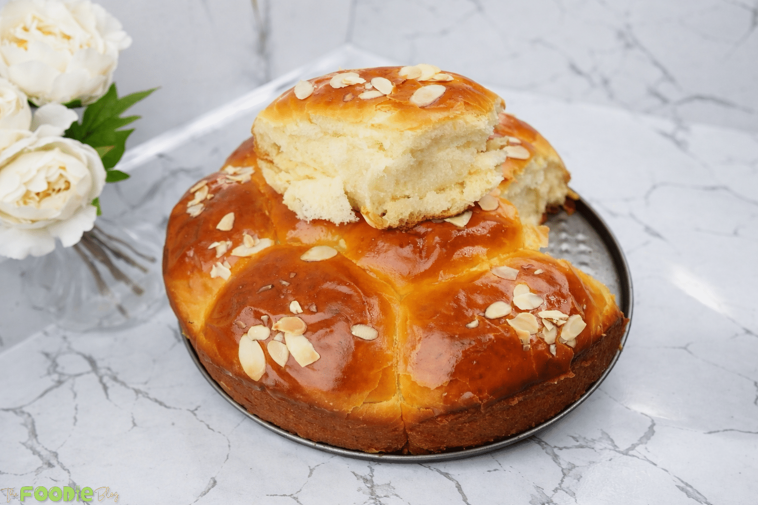 Soft homemade brioche bread dusted with powdered sugar and topped with almond flakes, photographed close up.