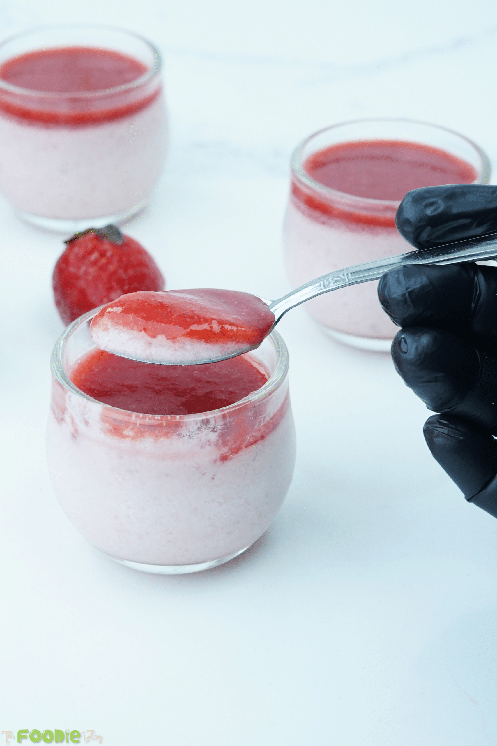 Spoon lifting a bite of strawberry panna cotta with strawberry topping