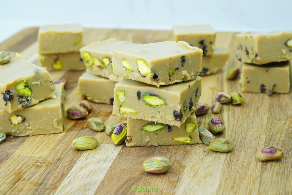 Stacked tahini fudge squares with pistachios on a wooden board