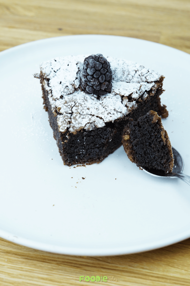 Slice of flourless chocolate almond cake dusted with powdered sugar on a plate