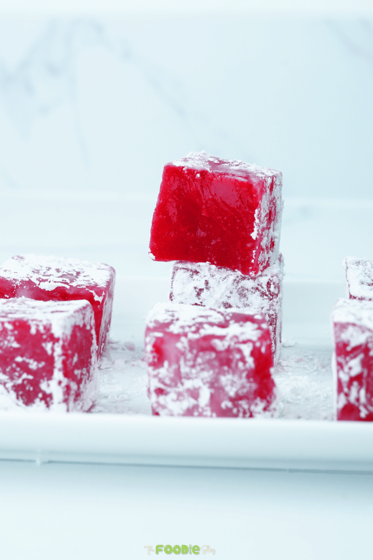 Red Turkish Delight cubes dusted with powdered sugar on a white tray
