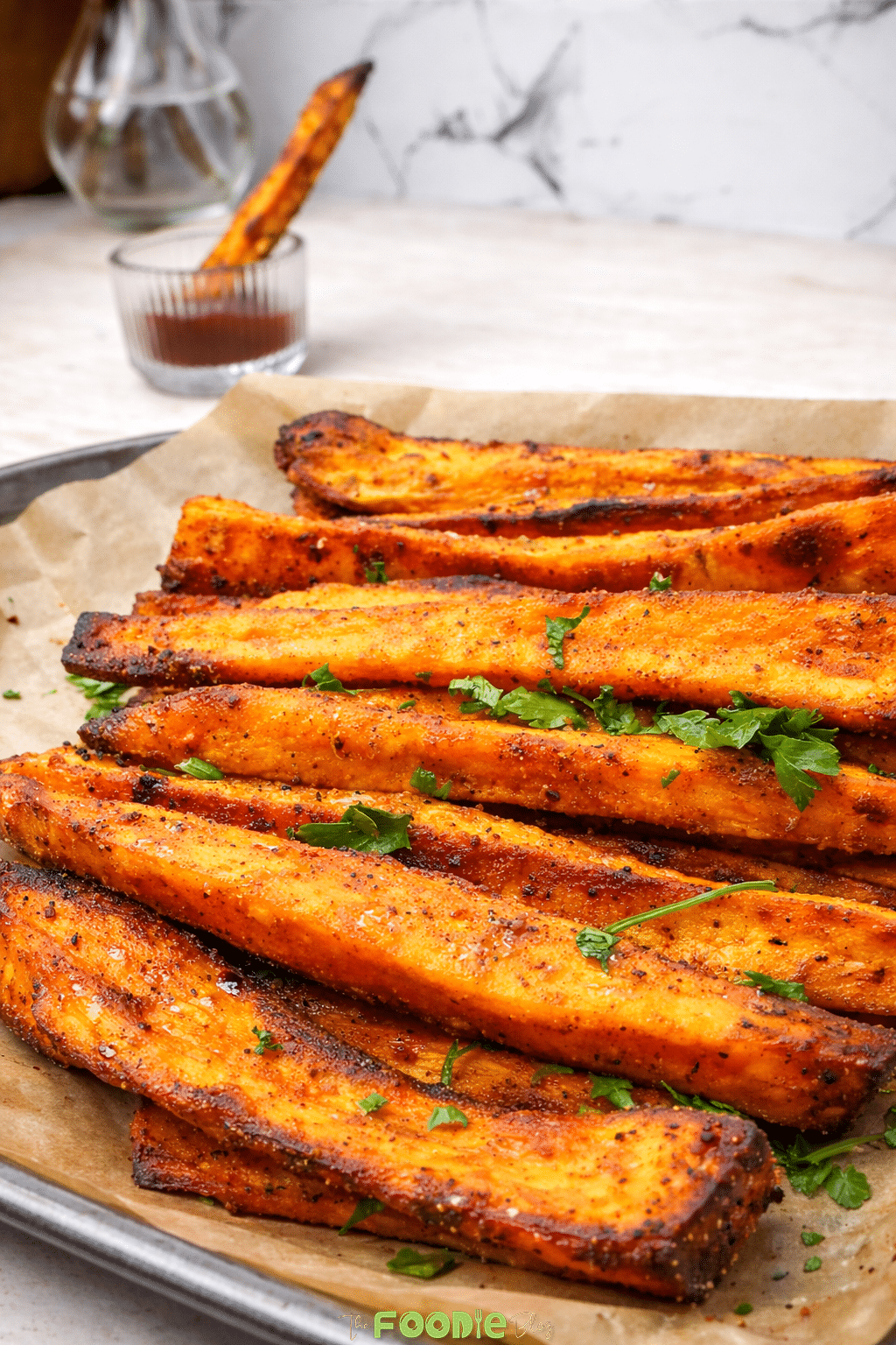 Ultimate sweet potato fries served on a plate with dipping sauce and fresh parsley