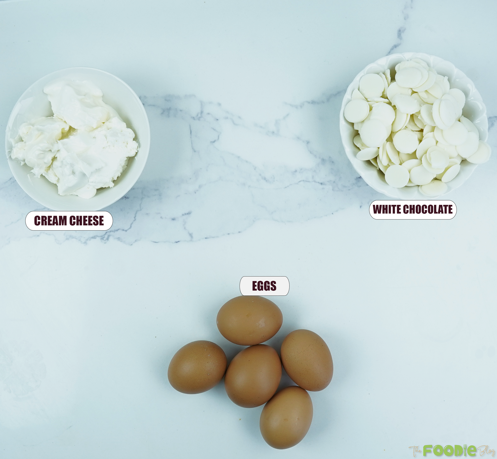 Ingredients for 3-ingredient Japanese cheesecake including cream cheese, white chocolate, and eggs arranged on a light surface