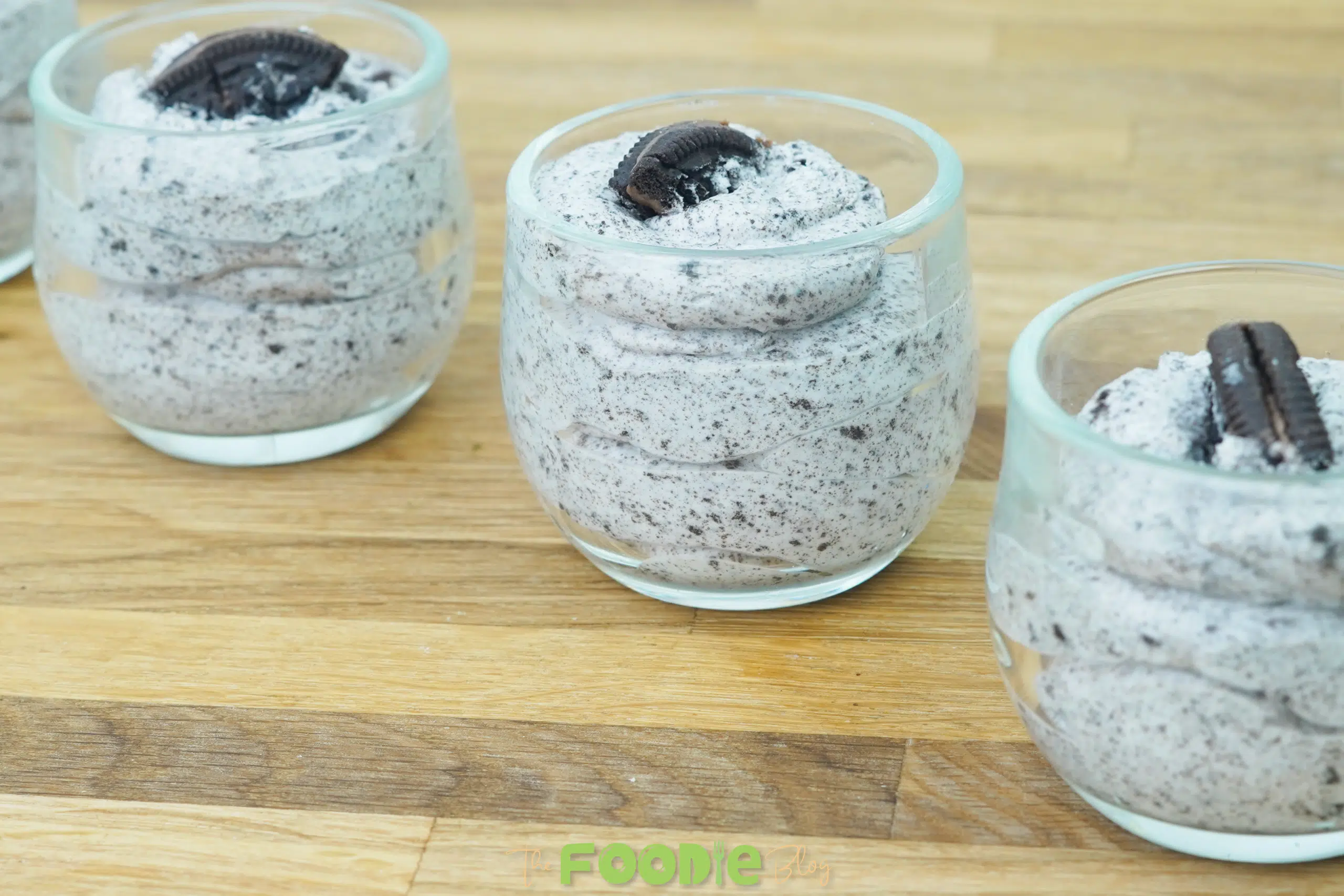 Three glasses of cookies and cream mousse on a wooden surface