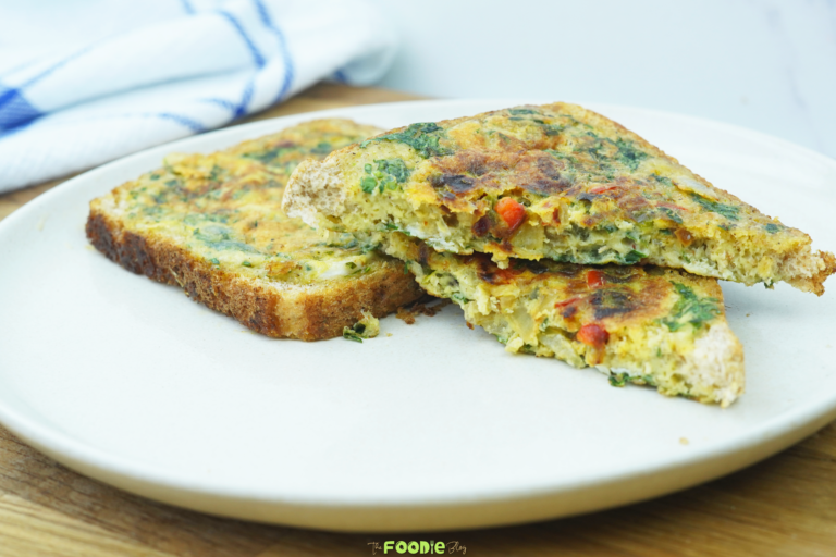 Two slices of bread omelette on a light plate with one piece stacked on top to show the filling