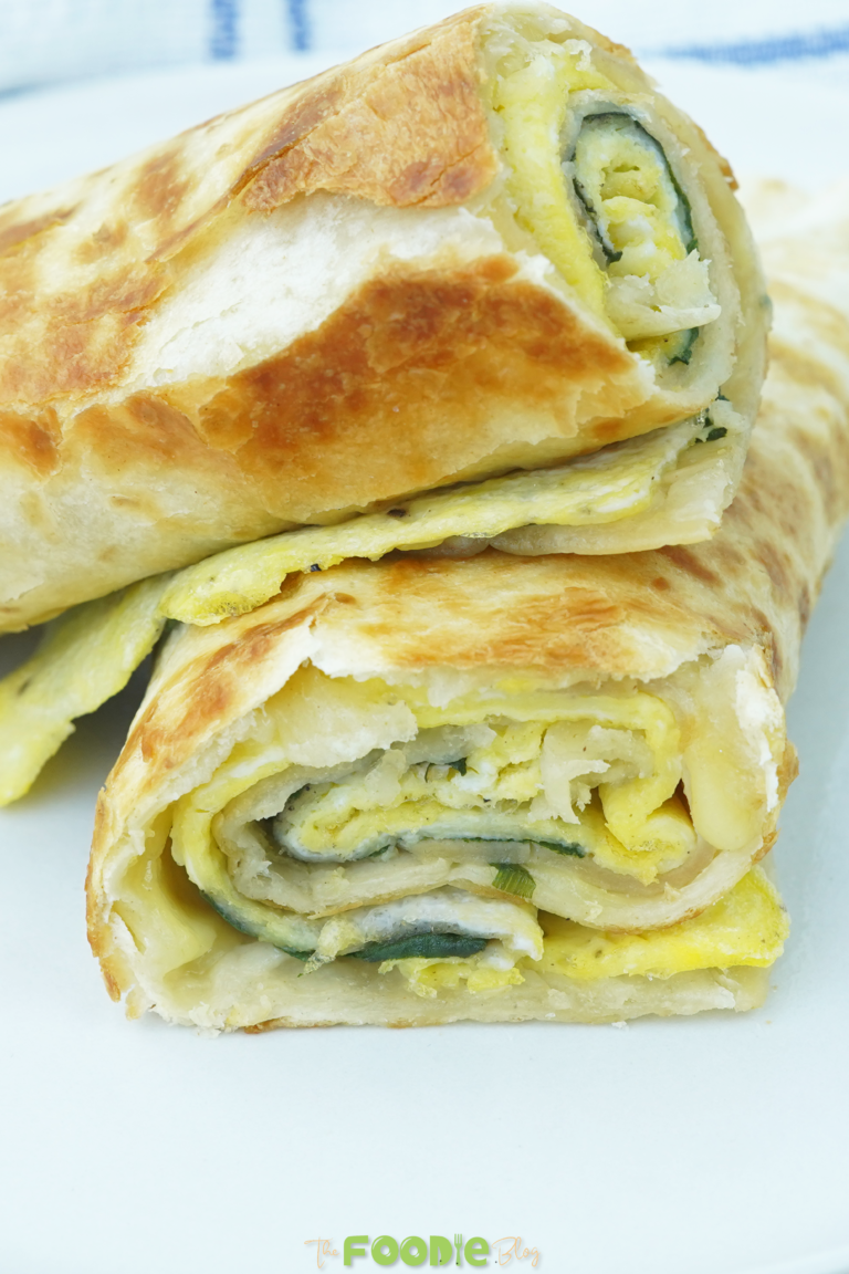 close-up of sliced breakfast borito showing egg, cheese, spinach, and tortilla layers
