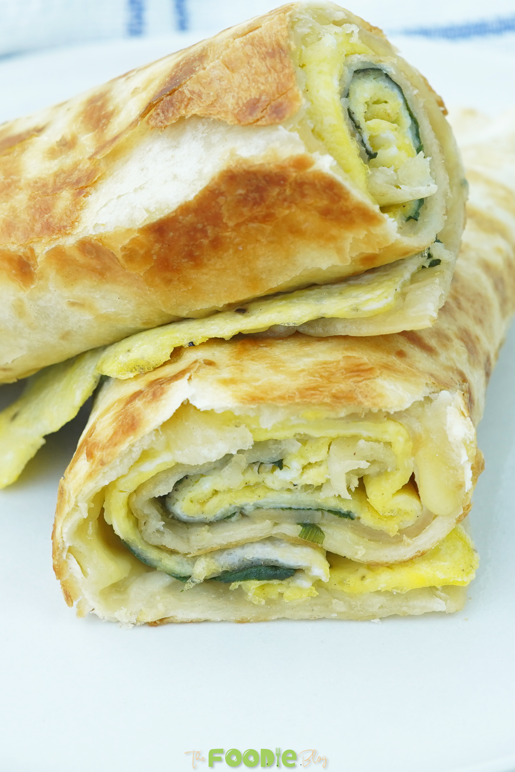 close-up of sliced breakfast borito showing egg, cheese, spinach, and tortilla layers