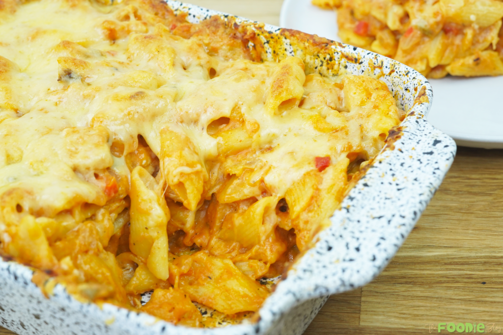 baked chicken pasta bake in a casserole dish with melted golden cheese on top
