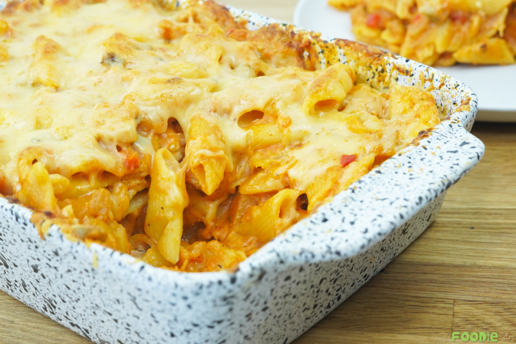 close-up of cheesy chicken pasta bake with penne pasta and creamy tomato sauce