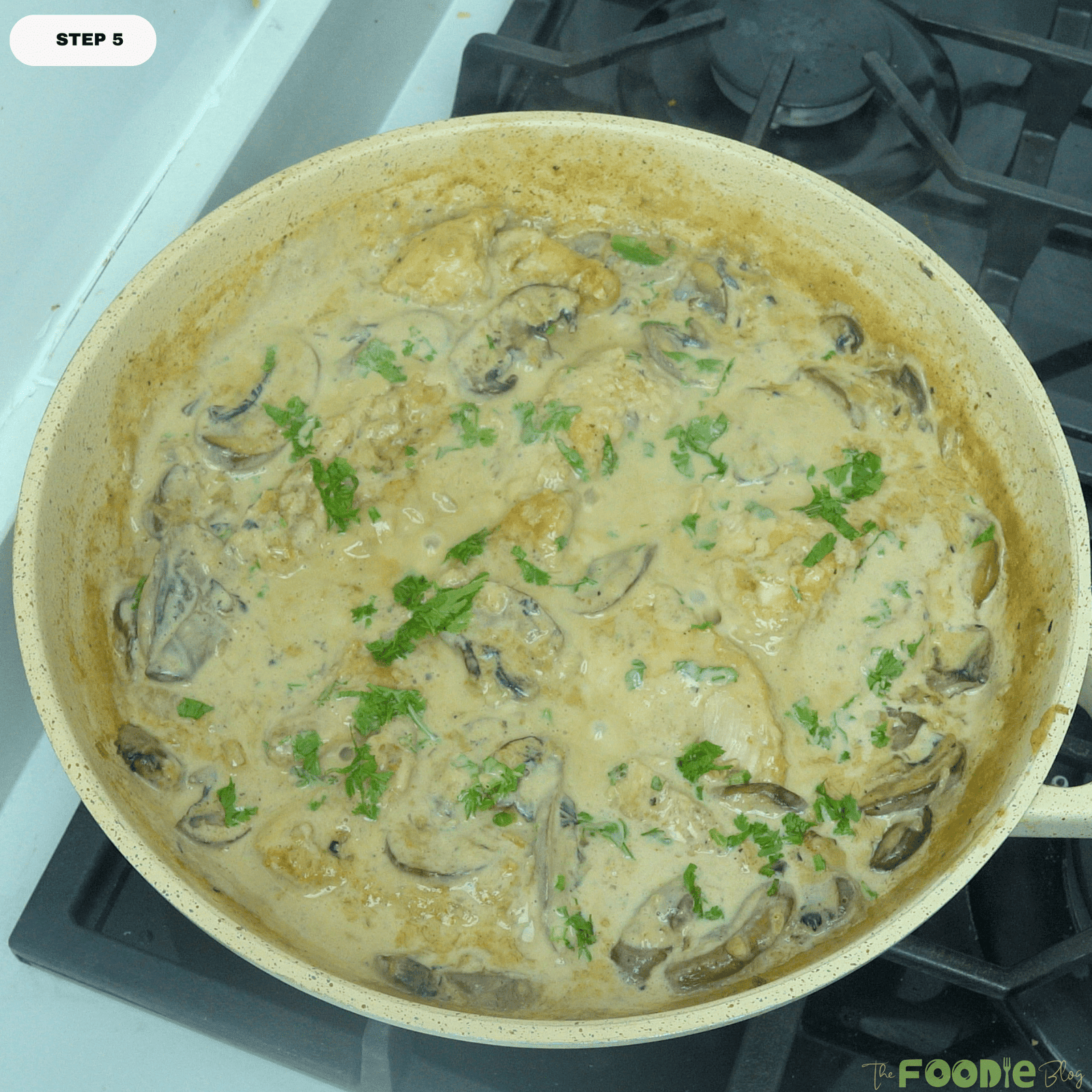 Finished creamy mushroom chicken in a skillet with parsley sprinkled over the top