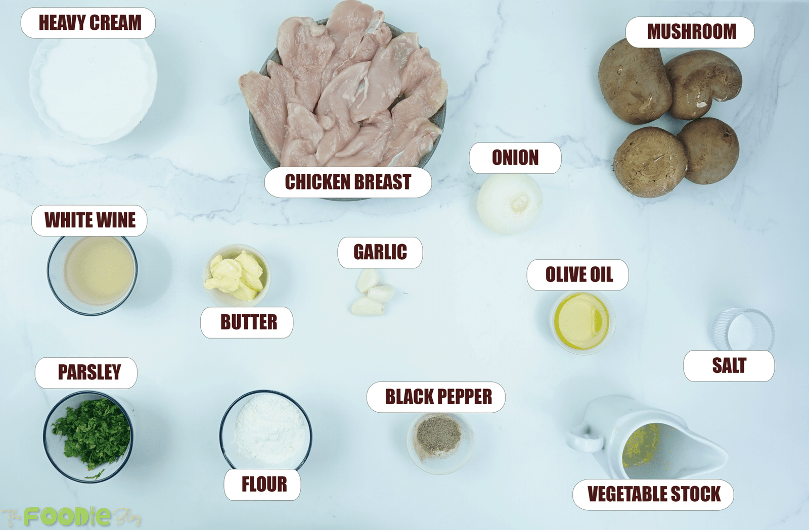 Overhead view of chicken breast, mushrooms, onion, cream, stock, garlic, butter, parsley, and seasonings for creamy mushroom chicken