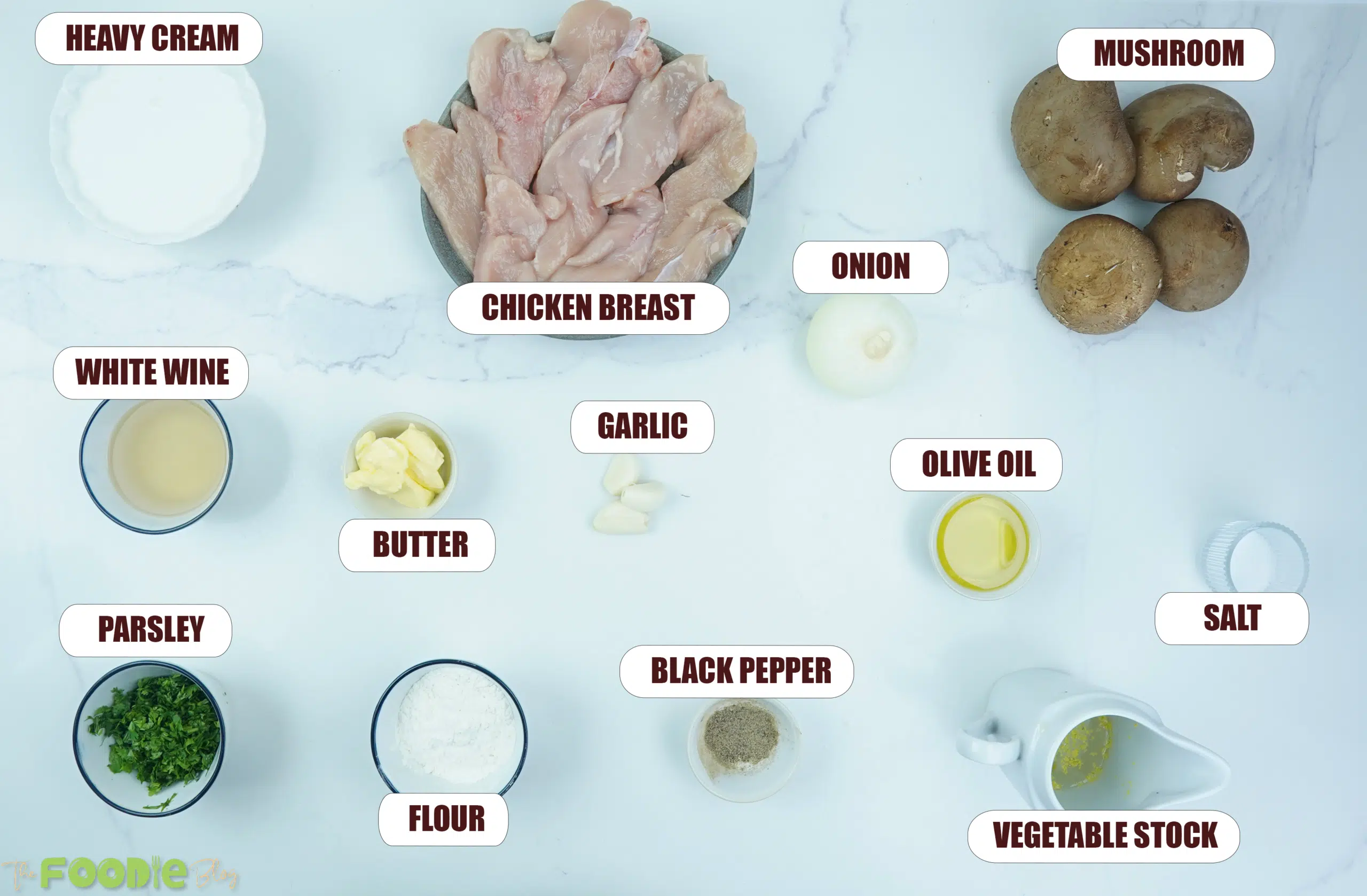 Overhead view of chicken breast, mushrooms, onion, cream, stock, garlic, butter, parsley, and seasonings for creamy mushroom chicken