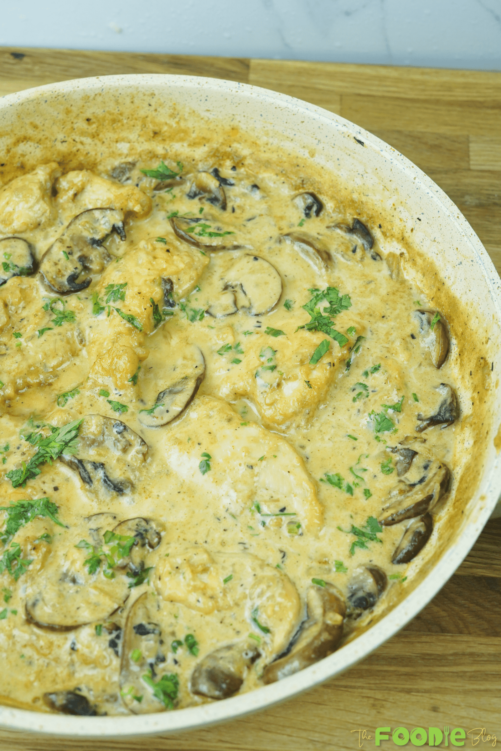 Creamy mushroom chicken simmering in a skillet with sliced mushrooms and parsley