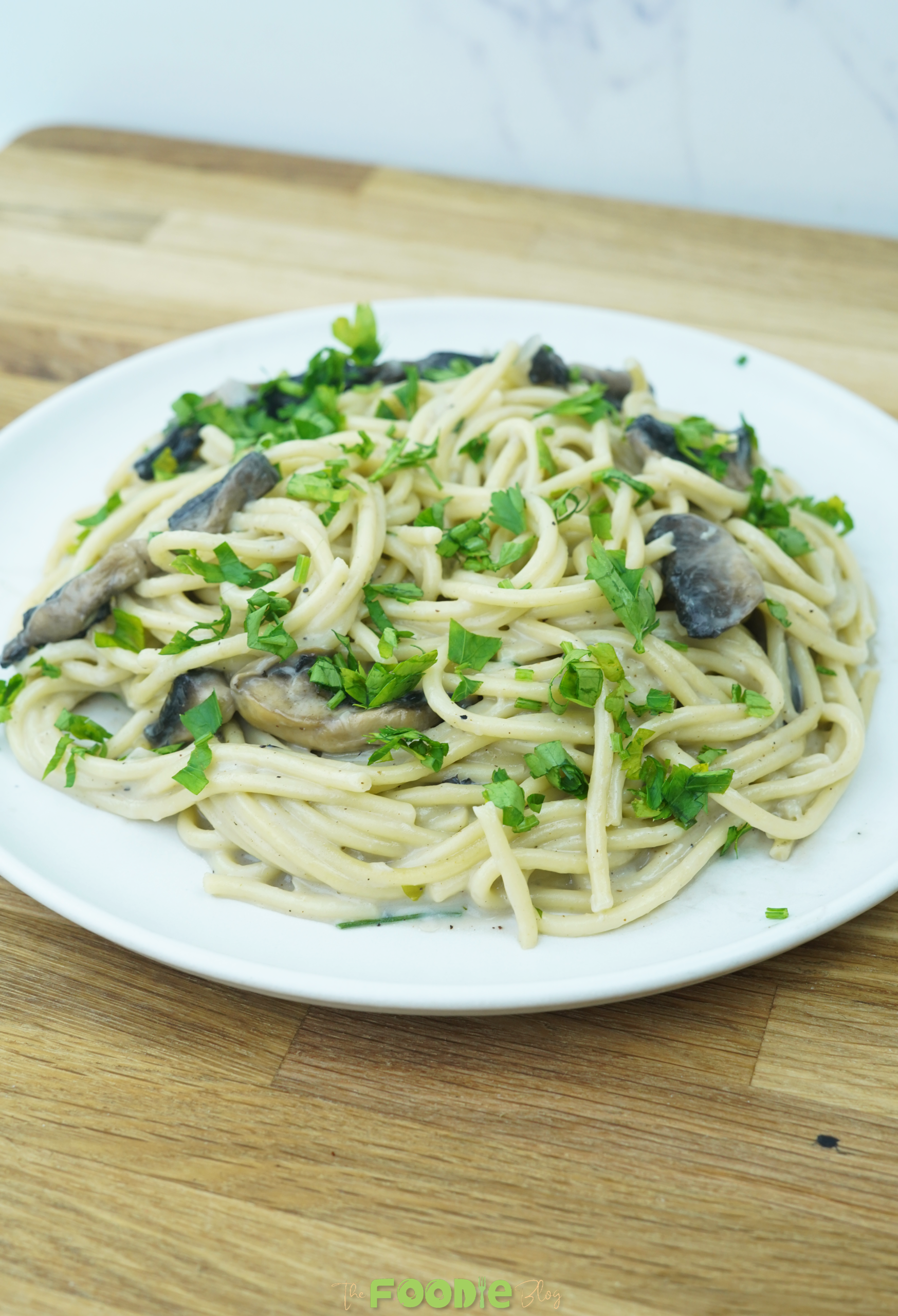 bowl of creamy mushroom pasta on a wooden counter with parsley garnish