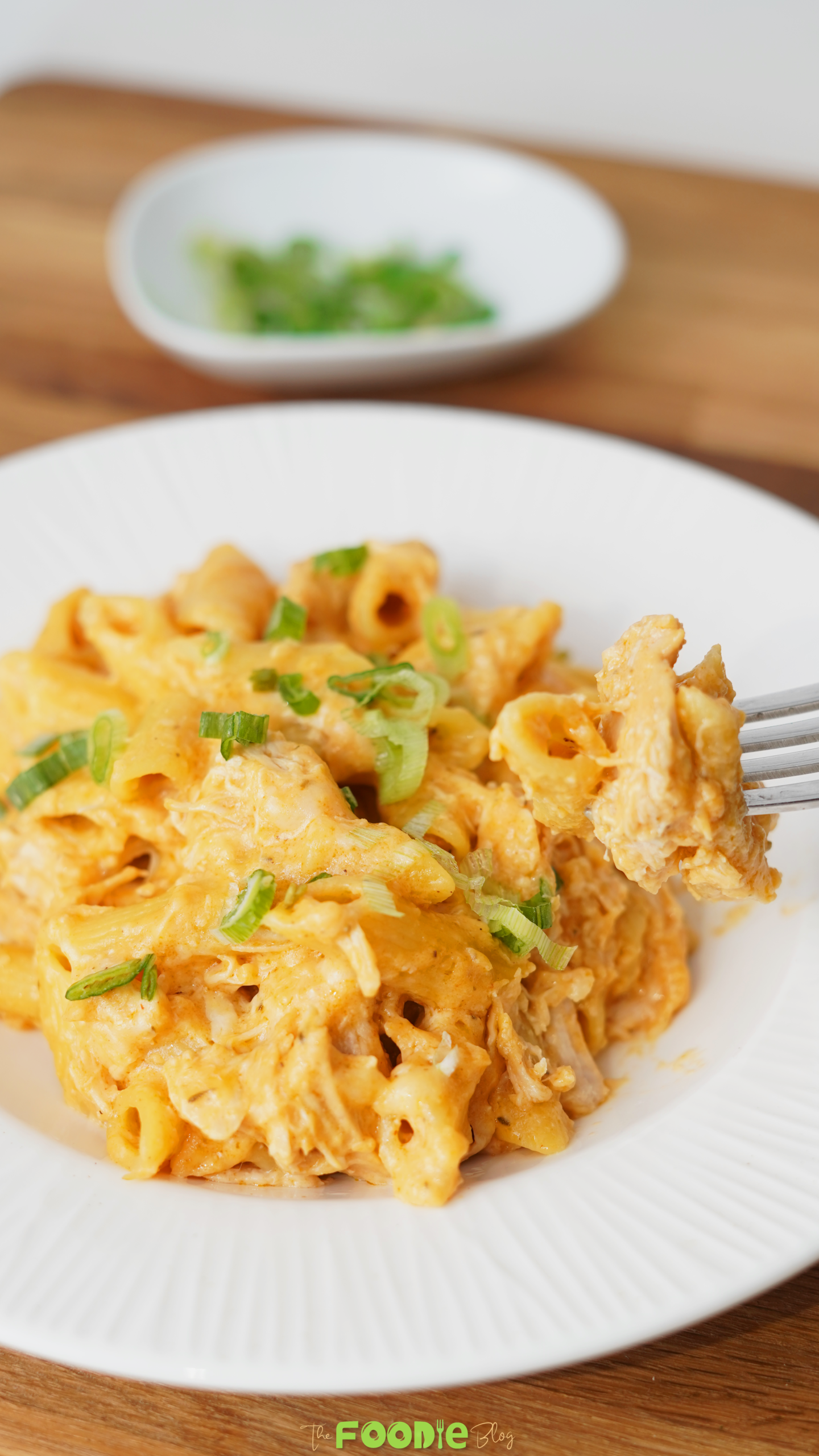 Creamy crockpot buffalo chicken pasta with penne in a pot topped with green onions