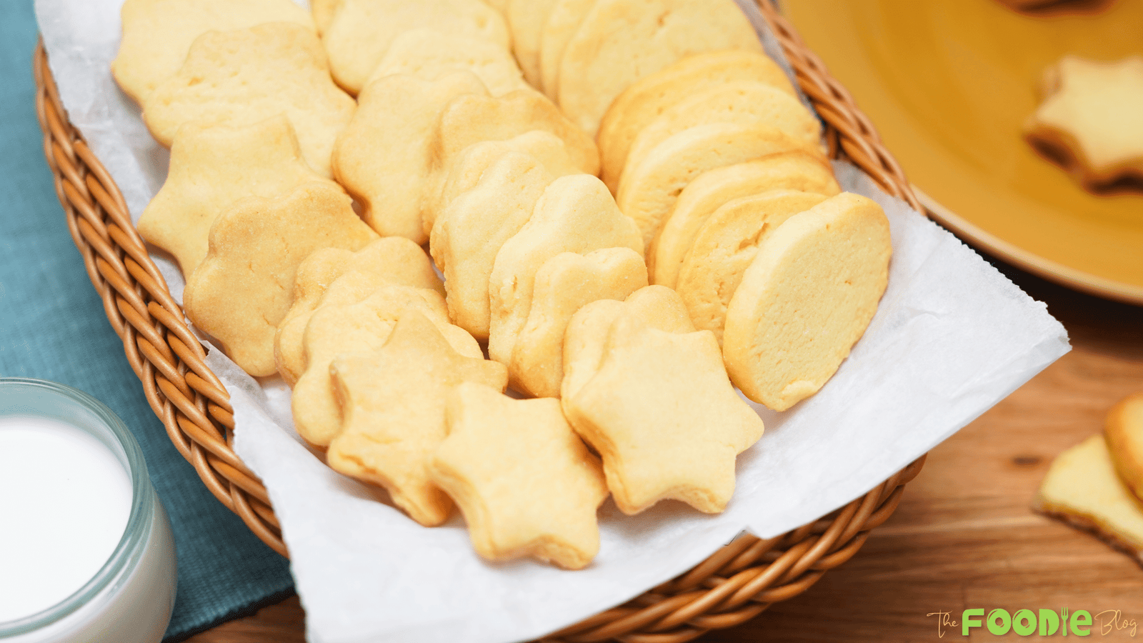 A basket filled with butter cookies in different shapes served with a glass of milk