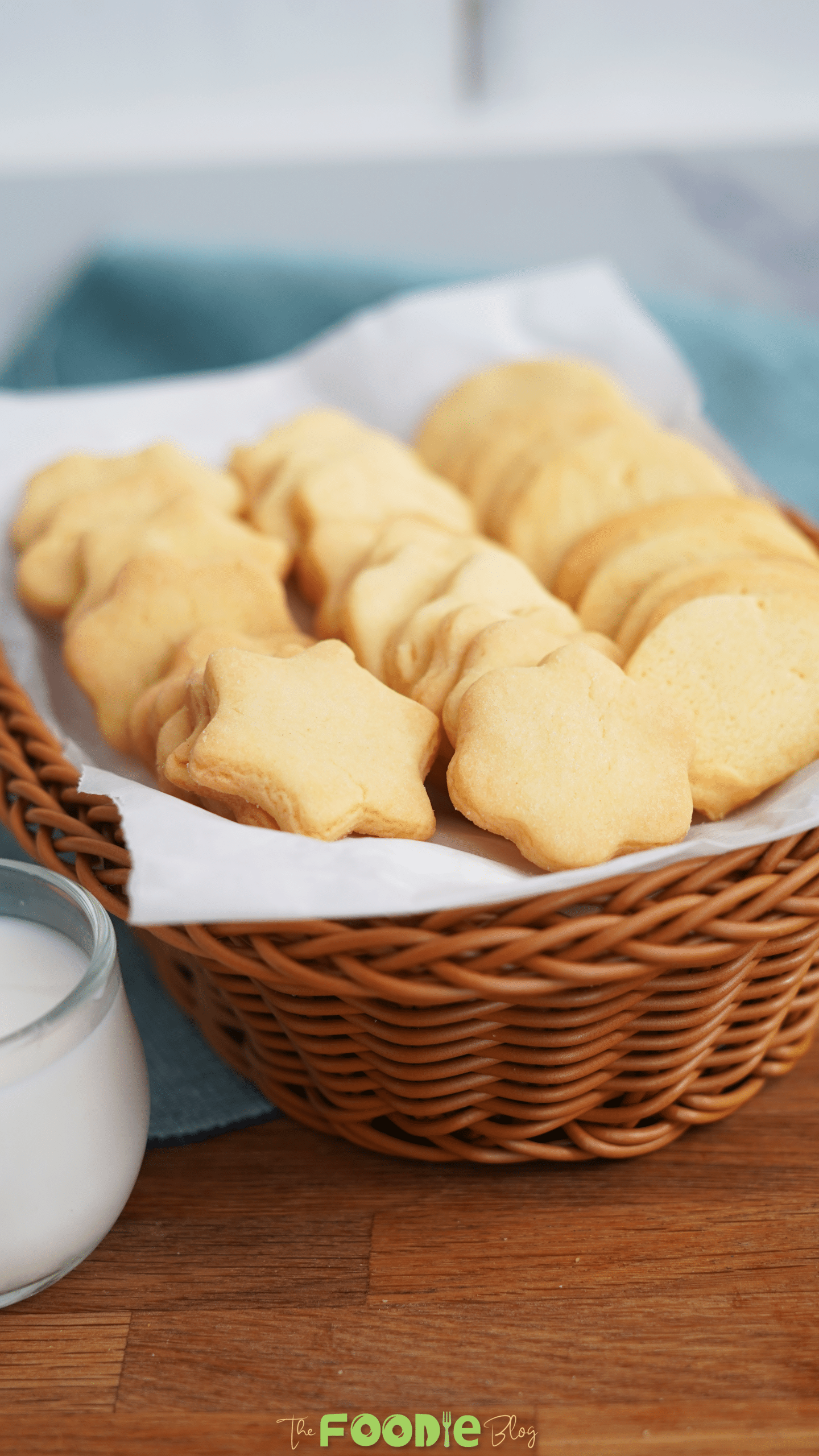 Butter cookies served in a basket lined with parchment paper next to a glass of milk